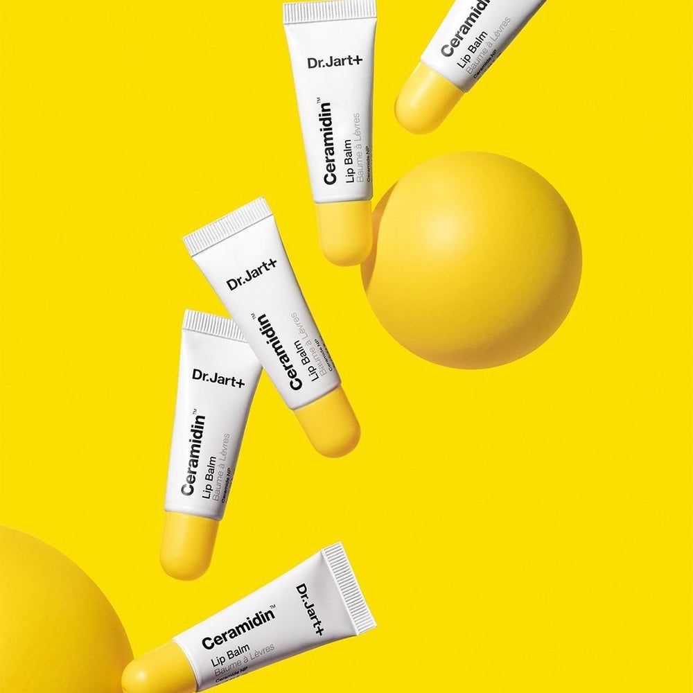 Mehrere Tuben Lip Balm auf gelbem Hintergrund. Gelbe Kugel.