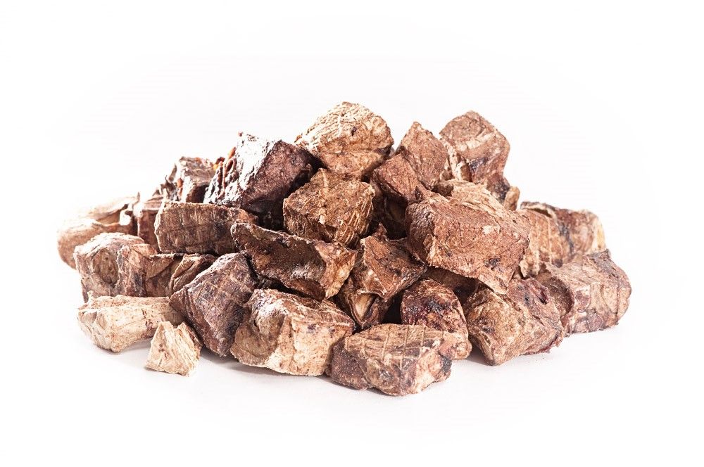 Haufen getrockneter, brauner Ziegen-Lungenwürfel. Einzelne Stücke unregelmäßig geformt, auf weißem Hintergrund.