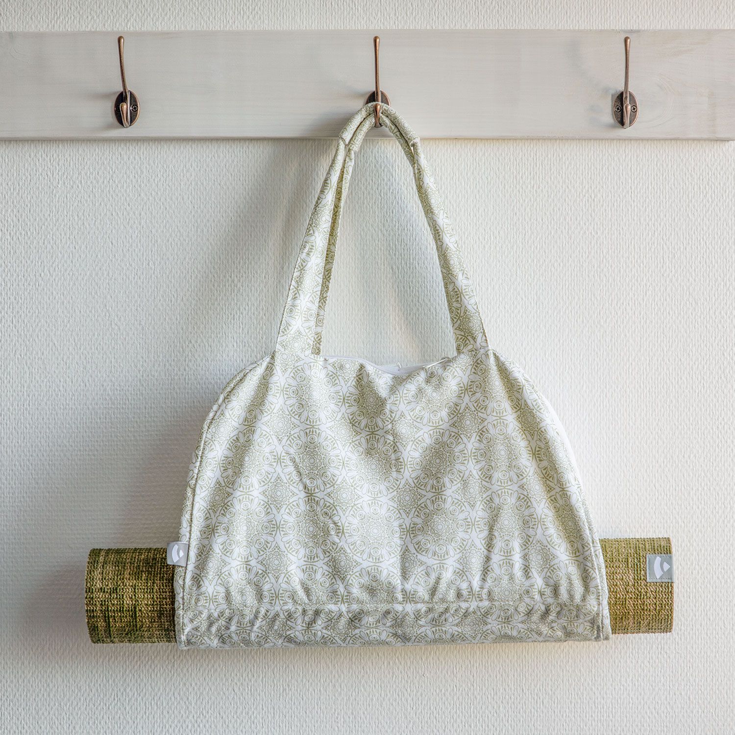 Yoga-Tasche mit gerolltem Yoga-Matte. An der Wand hängend. Ecru-farbenes Muster.