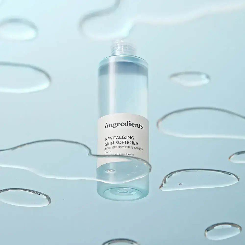 Transparente Flasche mit weißem Etikett, umgeben von Wassertropfen. Aufschrift: Ongredients, Revitalizing Skin Softener.