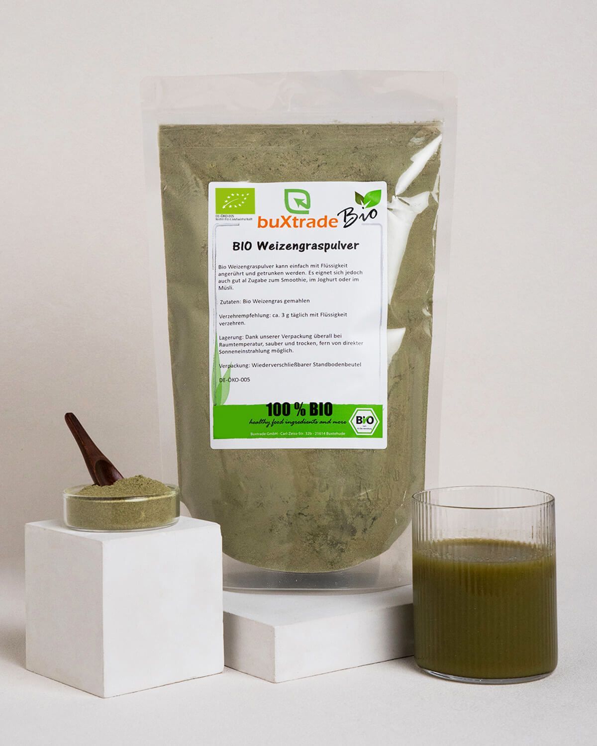 Verpackung von Bio Weizengraspulver, daneben ein Glas Getränk und eine Schale Pulver.