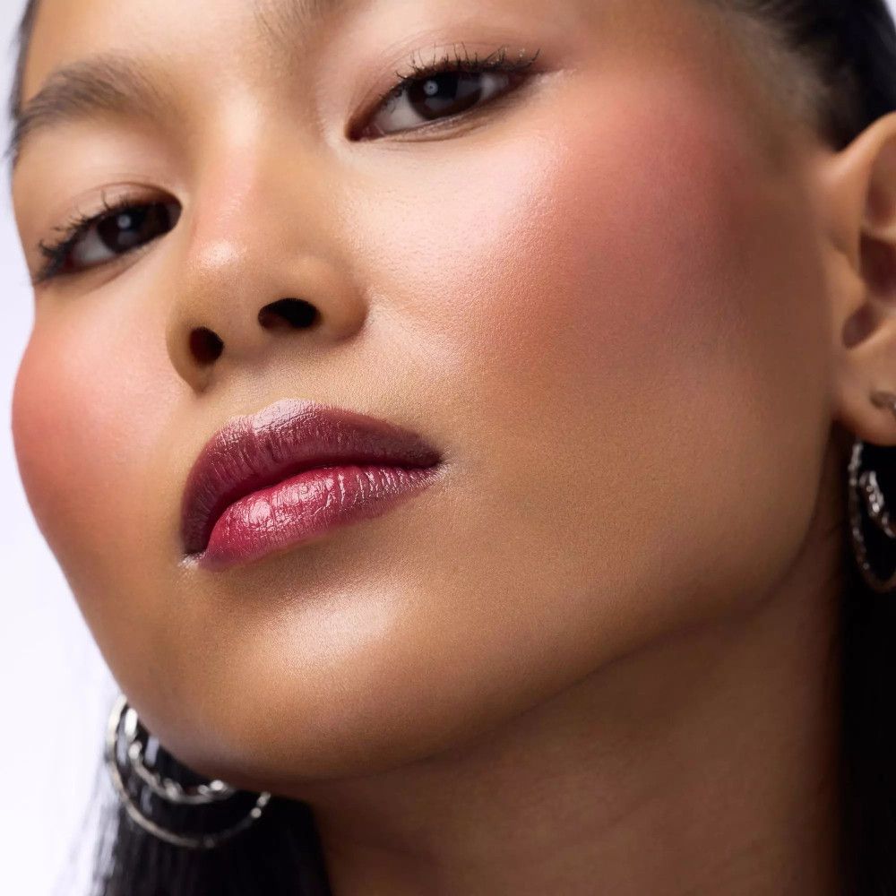 Nahaufnahme einer Person mit dunkelroten Lippen. Die Haut ist gebräunt. Die Lippen sind glänzend.