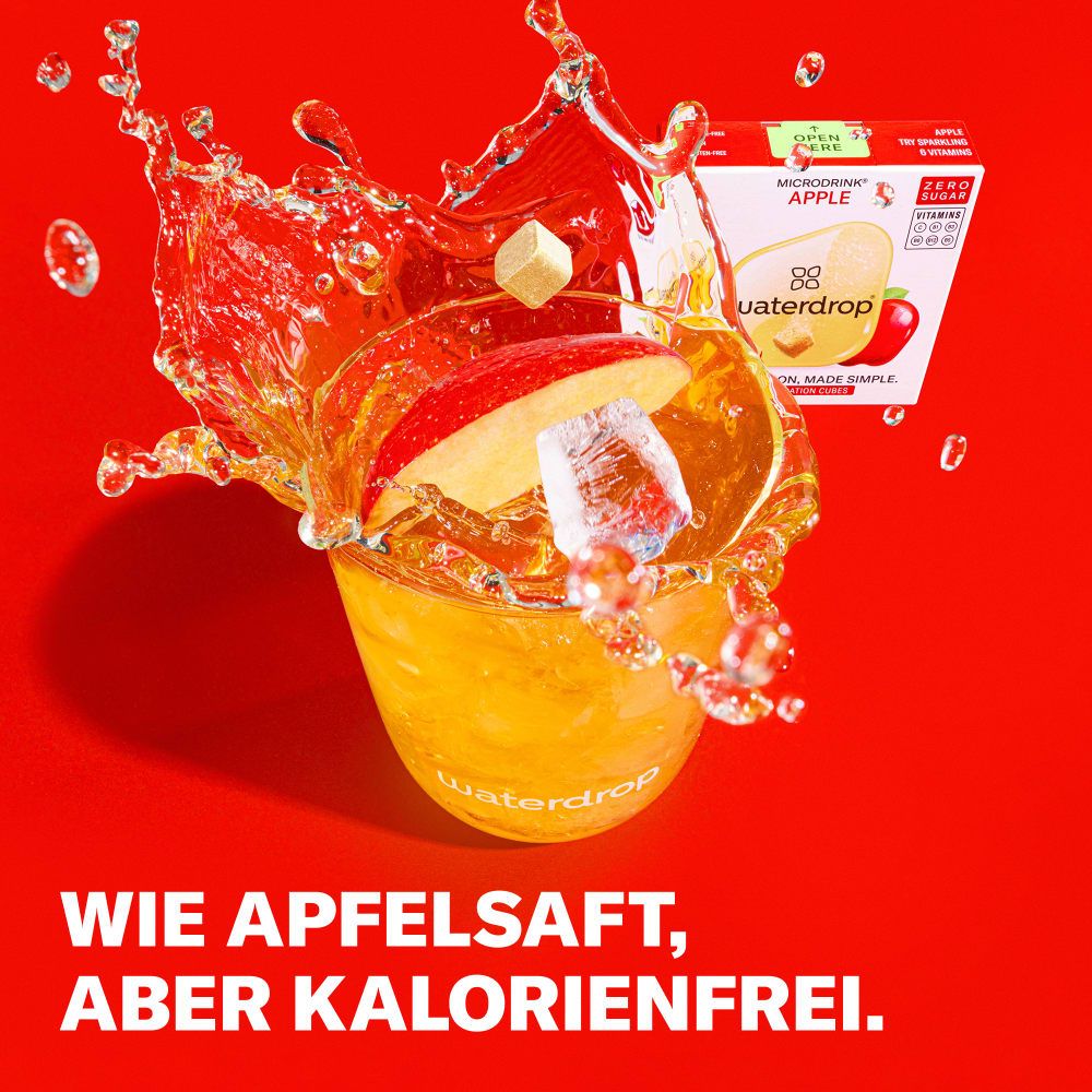 Ein Glas mit waterdrop® Microdrink Apfel, Apfelstückchen, Eiswürfeln und Spritzern.
