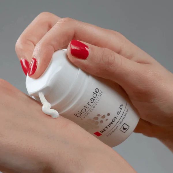 Weiße Flasche mit Aufschrift Biotrade, Retinol 0,3% und Nachtcreme-Gesichtsmaske. Creme wird auf die Haut aufgetragen.