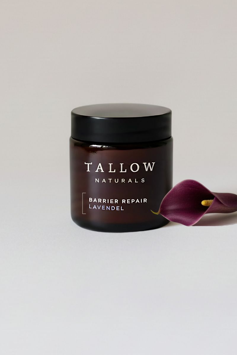 Braunes Glas mit schwarzem Deckel. Aufschrift: TALLOW NATURALS, BARRIER REPAIR LAVENDEL. Daneben eine lila Calla.