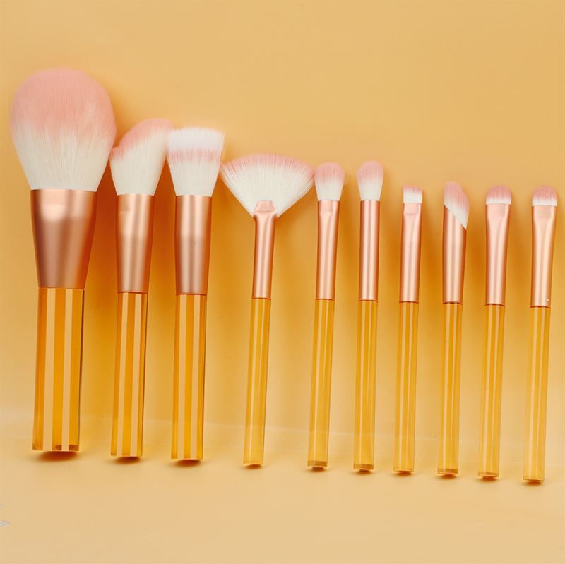 Make-up-Pinsel-Set mit transparenten, orangefarbenen Griffen und rosa Borsten. Verschiedene Formen und Größen.