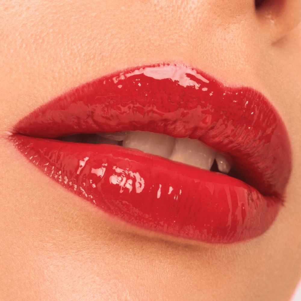 Nahaufnahme von roten, glänzenden Lippen. Die Lippen sind geöffnet und zeigen Zähne.