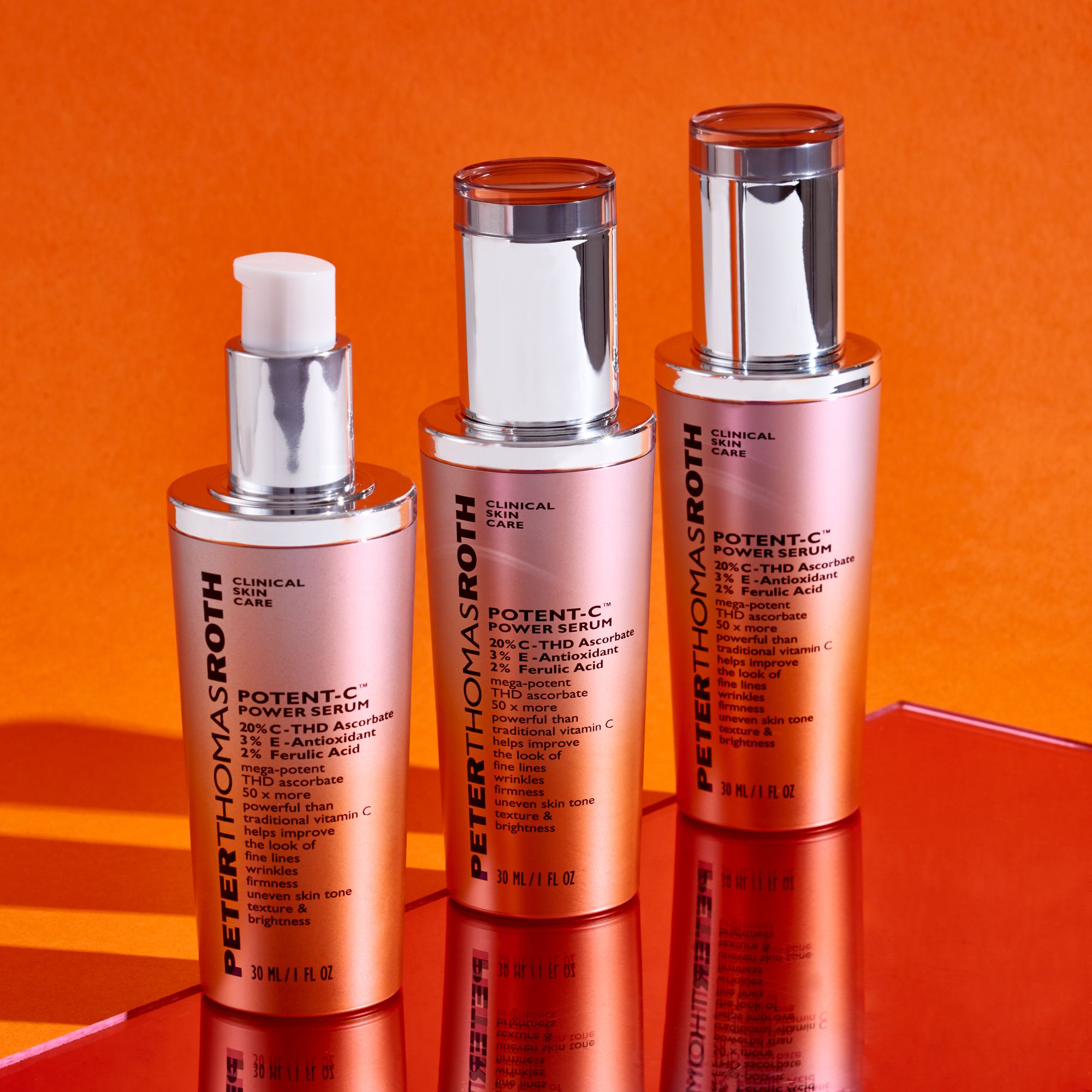 Drei Serumflaschen. Aufschrift: Potent-C Power Serum. Silberne Kappen und orangefarbener Farbverlauf. Auf orangefarbenem Hintergrund.