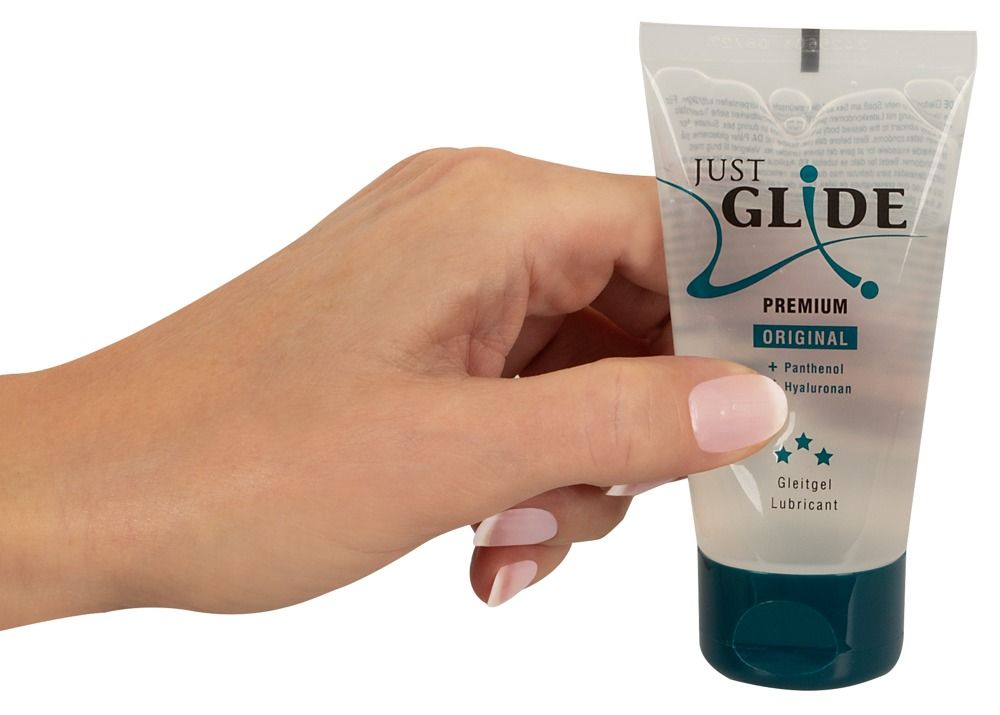 Hand hält transparente Tube mit blauem Verschluss. Aufschrift: JUST GLIDE PREMIUM ORIGINAL. Medizinische Gleitgel.