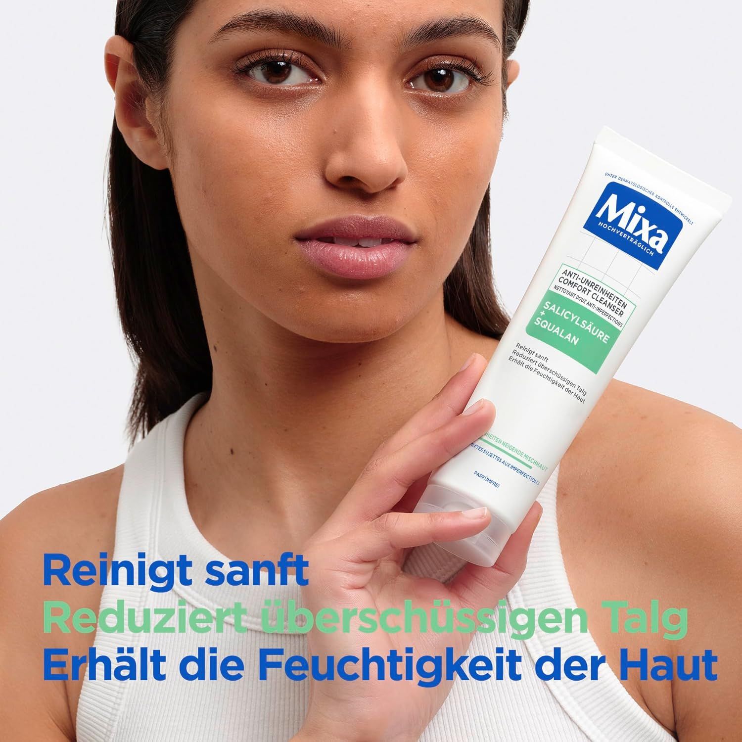 Frau hält eine Tube. Auf der Tube steht Mixa Anti-Unreinheiten Comfort Cleanser. Text: Reinigt sanft, reduziert überschüssigen Talg, erhält die Feuchtigkeit.