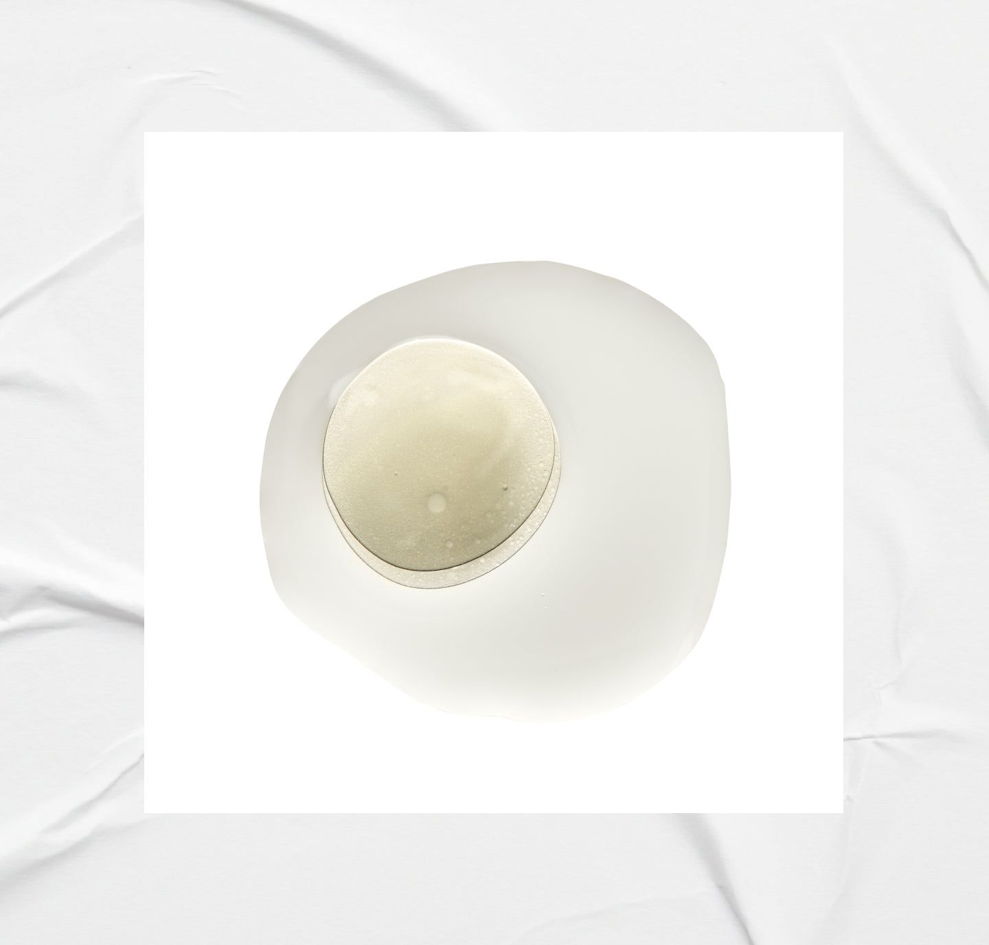 Weißer Hintergrund mit einem Tropfen Flüssigkeit und einem runden Objekt in der Mitte.