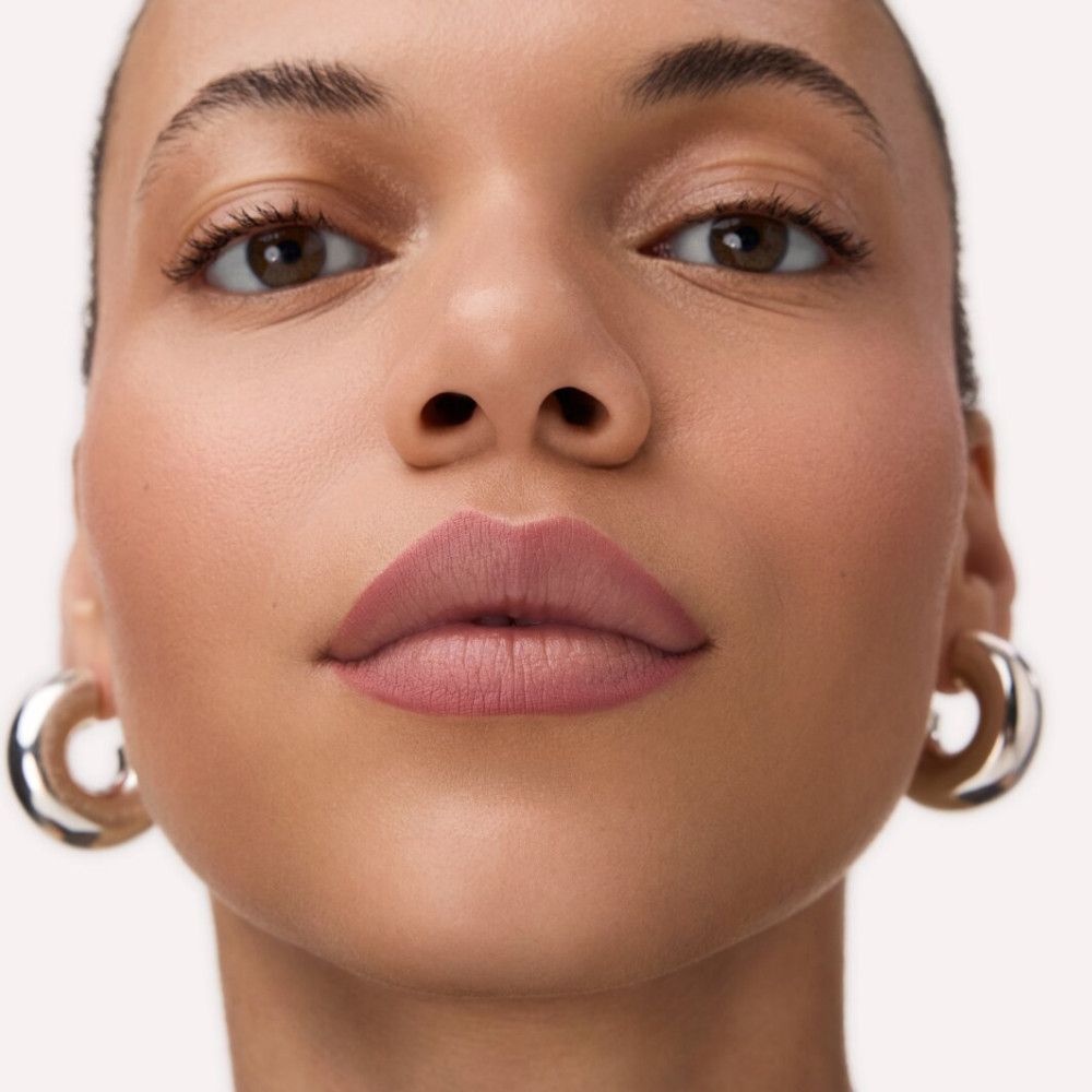 Nahaufnahme eines Gesichts mit rosafarbenen Lippen. Frau mit silbernen Creolen.