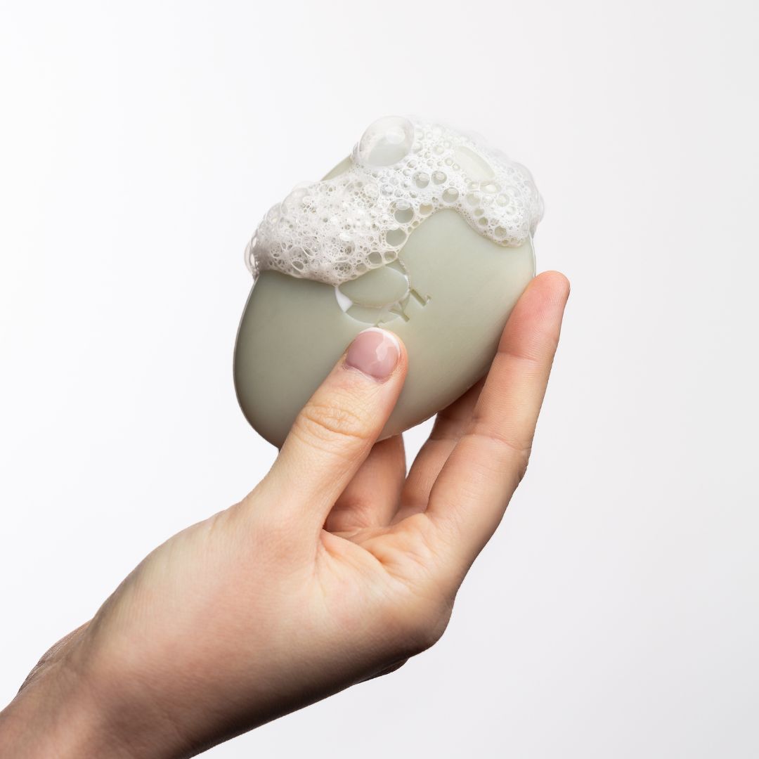 Ovale Seife in Hand mit Schaum bedeckt. 