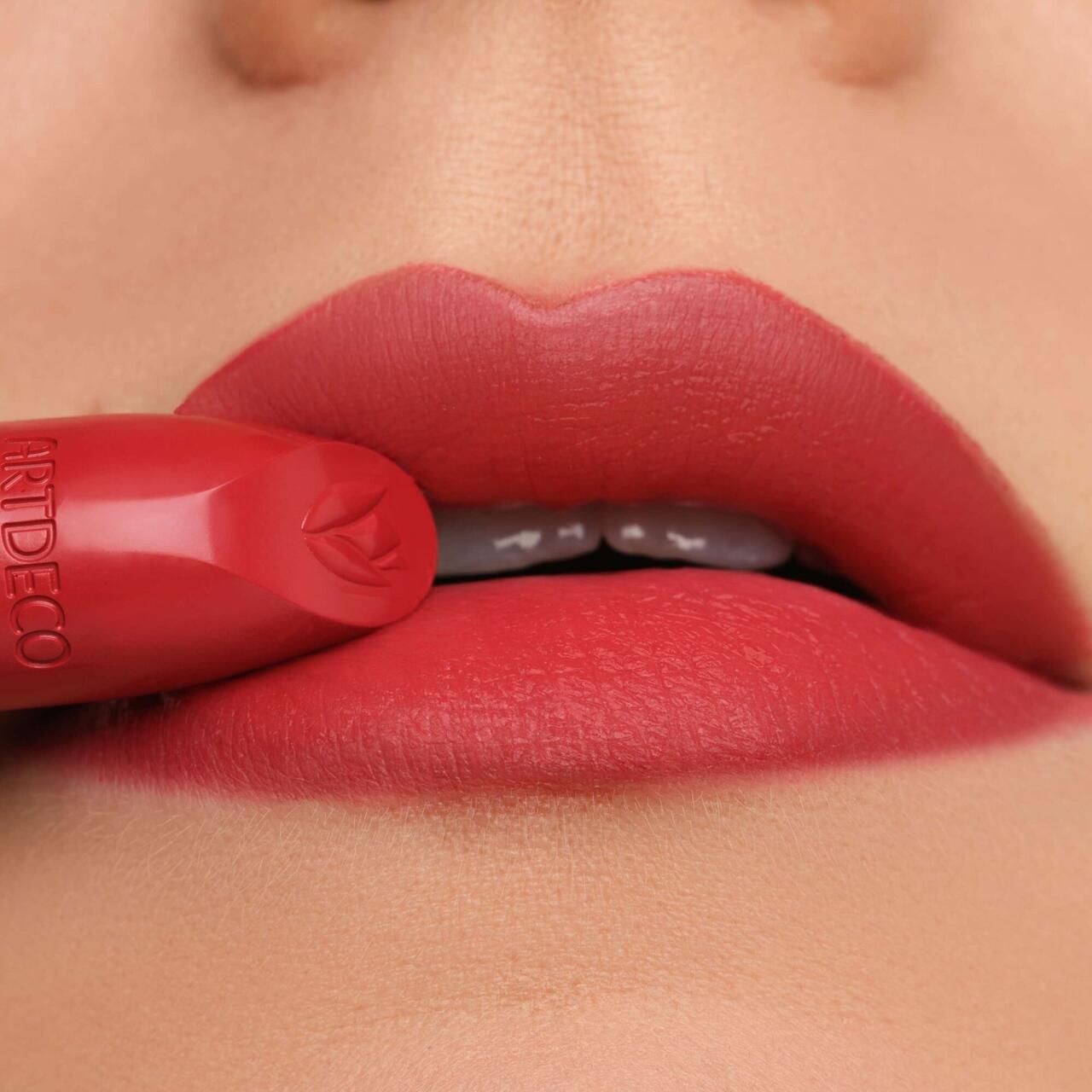 Lippenstift berührt Lippen. Roter Lippenstift mit Logo und Schriftzug ARTDECO. Lippen in Rot. Nahaufnahme.