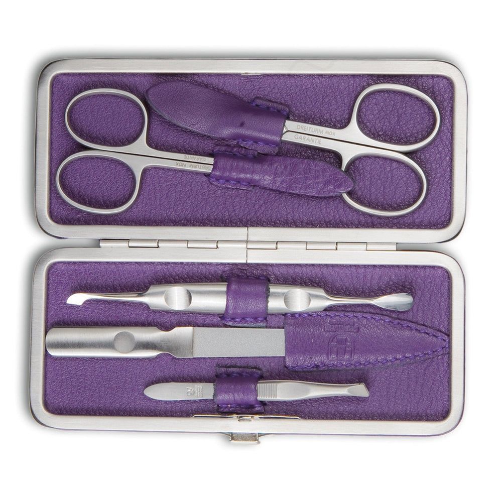 Maniküre-Set in lila Etui. Enthält Nagelschere, Feile und weitere Werkzeuge. Metall und Leder. Geöffnet.