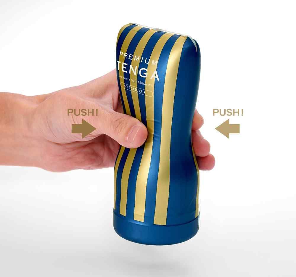 Blau-gold gestreiftes Produkt in Hand gehalten. Aufschrift: PREMIUM TENGA. Pfeile mit 'PUSH!' zeigen die Anwendung an.