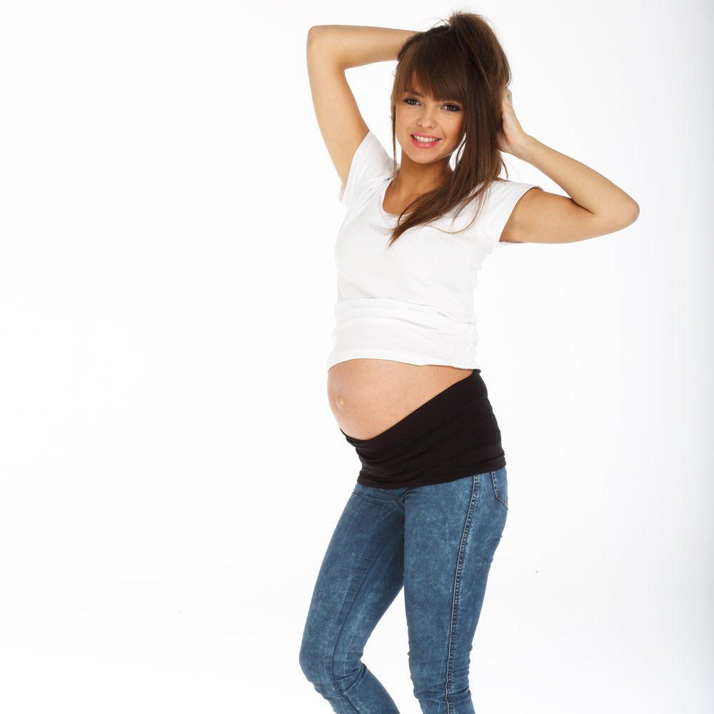 Schwarzes Bauchband aus Tencel. Die Frau trägt Jeans und ein weißes Oberteil. Sie lächelt.