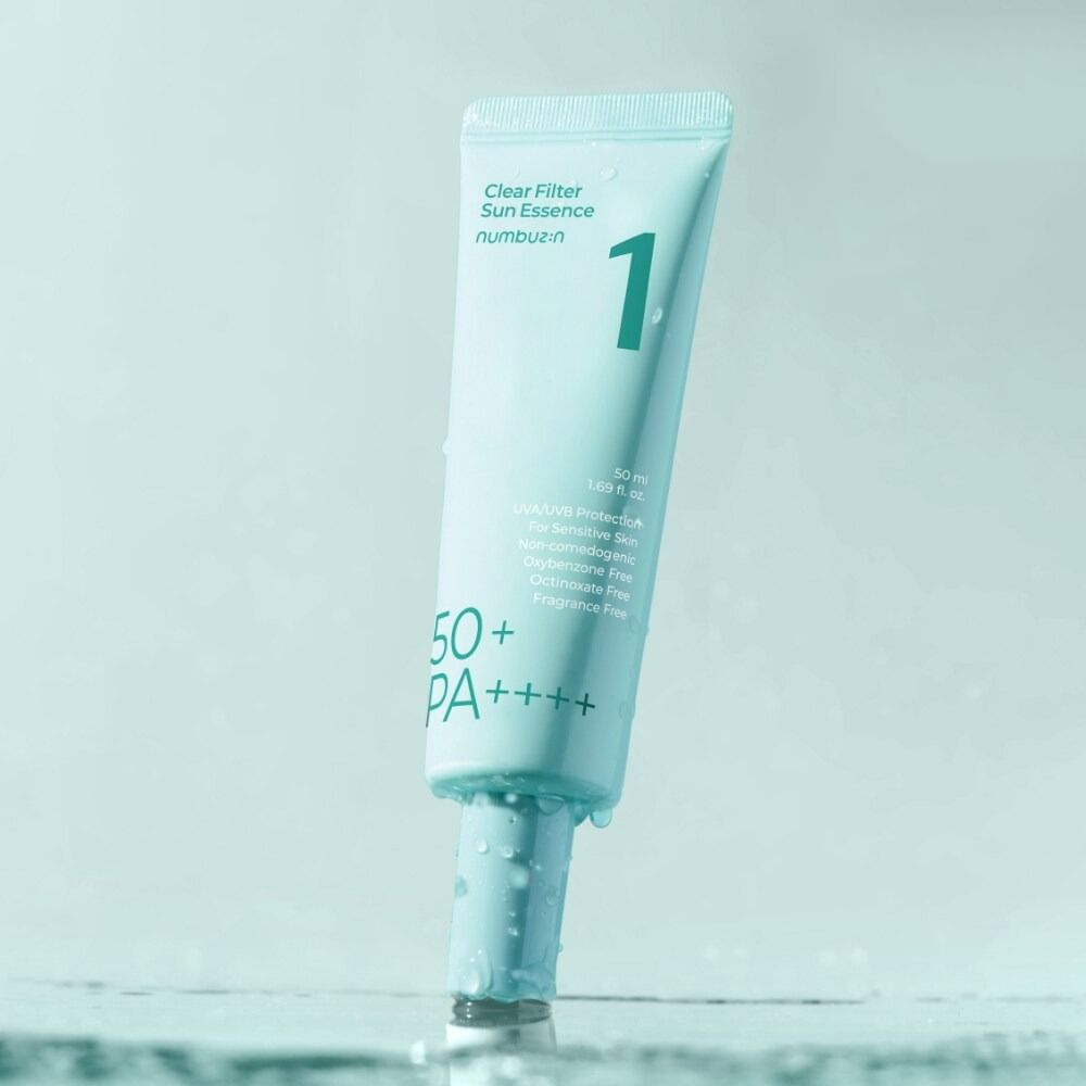 Hellgrüne Tube "Clear Filter Sun Essence" mit "1" und SPF 50+ PA++++. Produkt im Wasser platziert, Tropfen am Tubenhals.