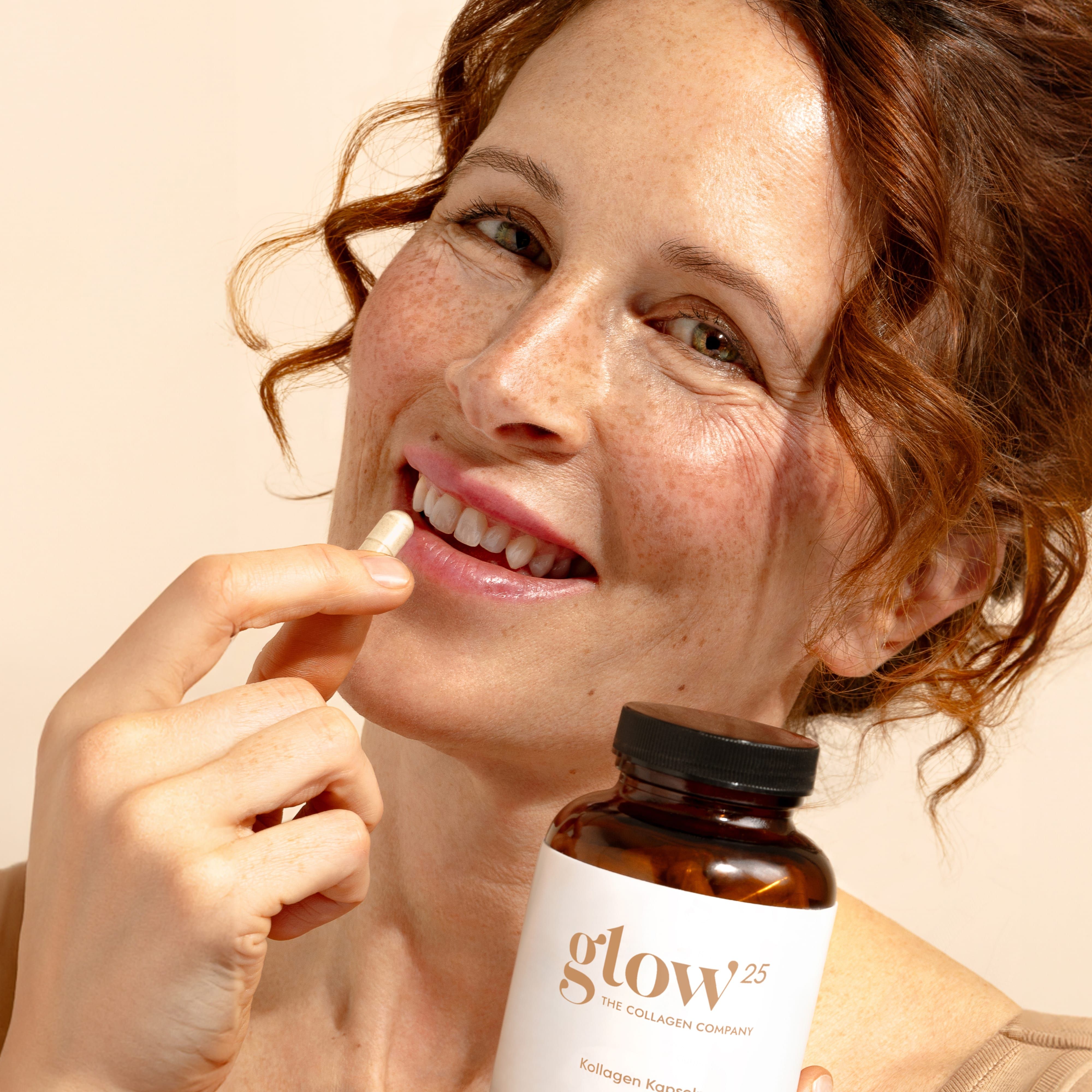 Frau hält Kapsel zwischen den Zähnen. Braune Flasche im Hintergrund. Aufschrift: Glow25, Kollagen Kapseln.