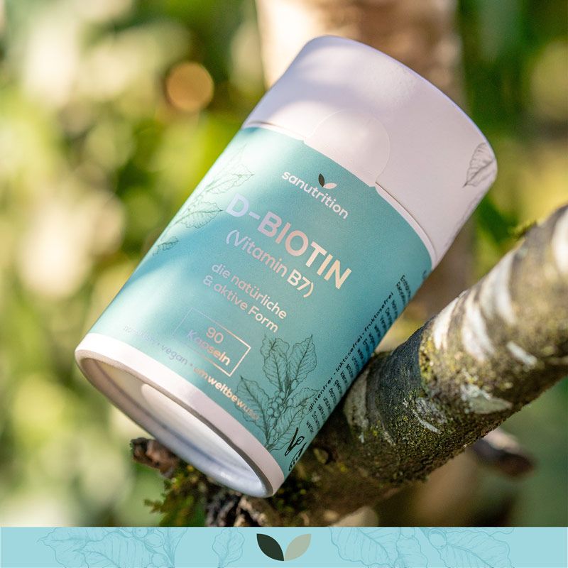 Zylindrische Dose Sanutrition D-Biotin (Vitamin B7) auf einem Ast. Türkis-weiße Verpackung mit Produktinformationen und Blättermuster.