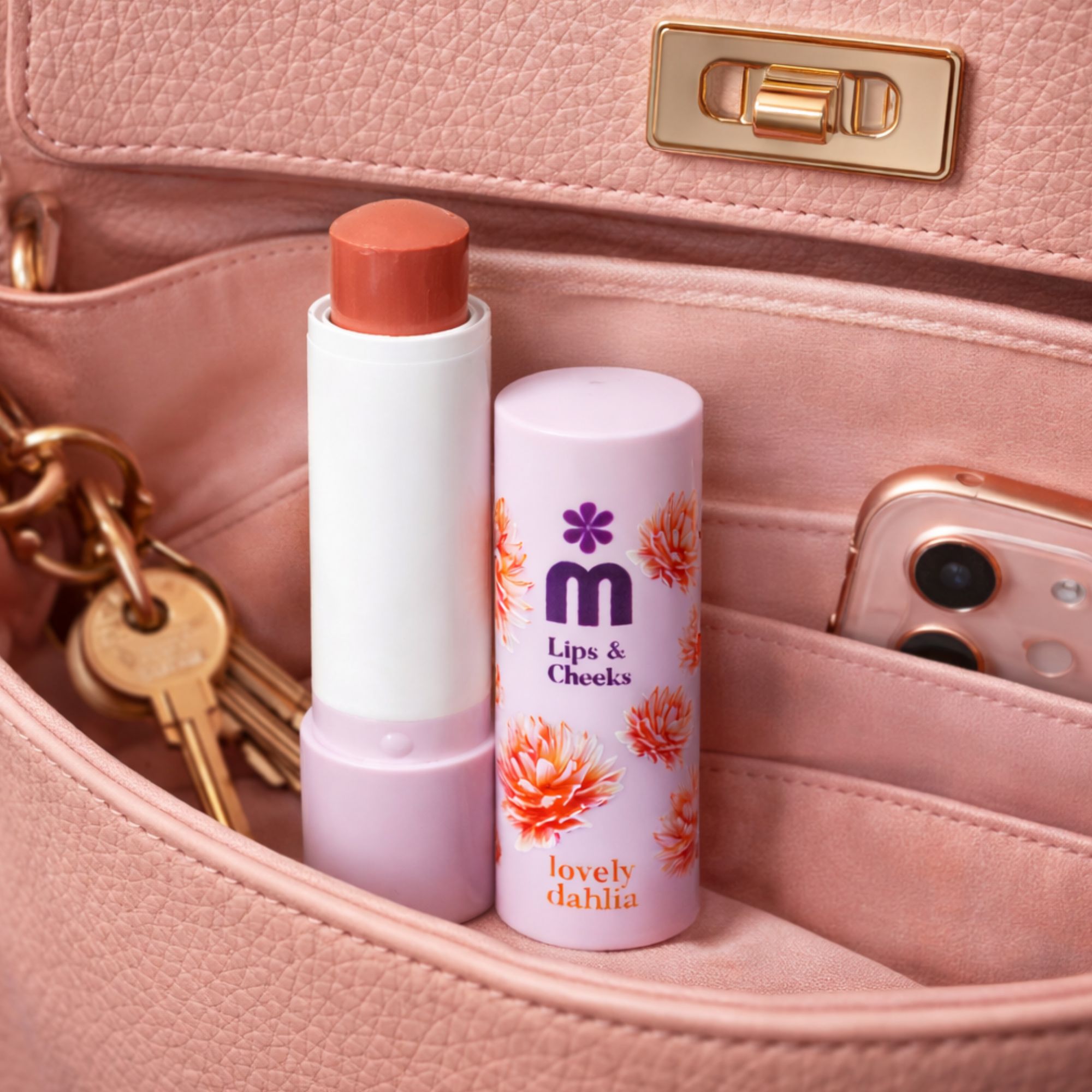 Lippen- und Wangenbalsam in einer Handtasche. Weißer Stift mit rosafarbenem Balsam. Daneben ein Handy.