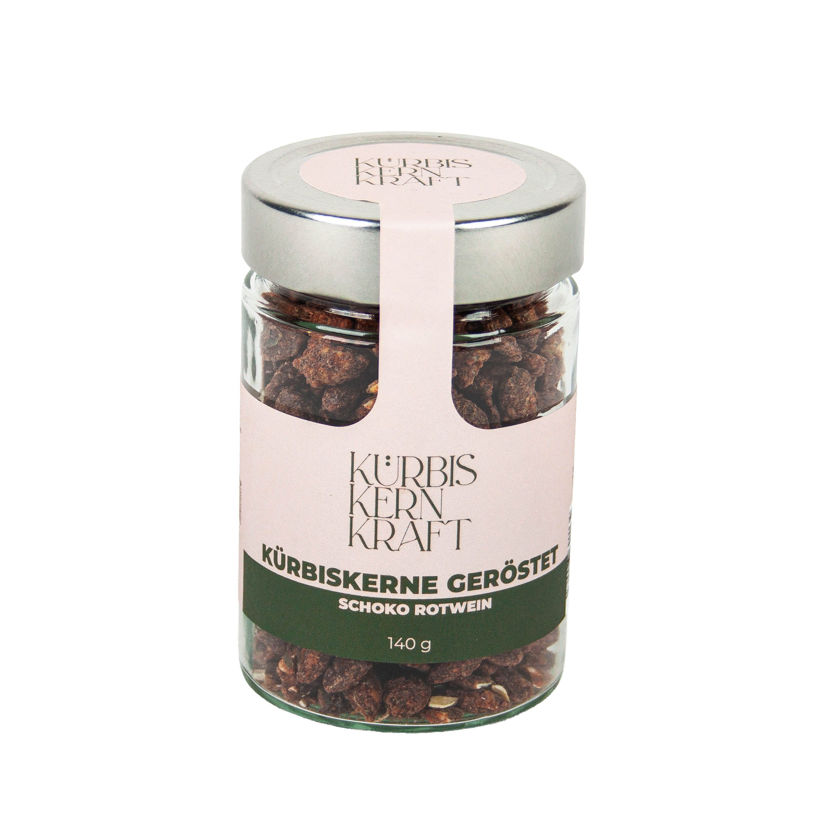 Glas mit gerösteten Kürbiskernen. Rosa Etikett mit Schriftzug: Kürbis Kern Kraft, Kürbiskerne geröstet Schoko Rotwein, 140 g.