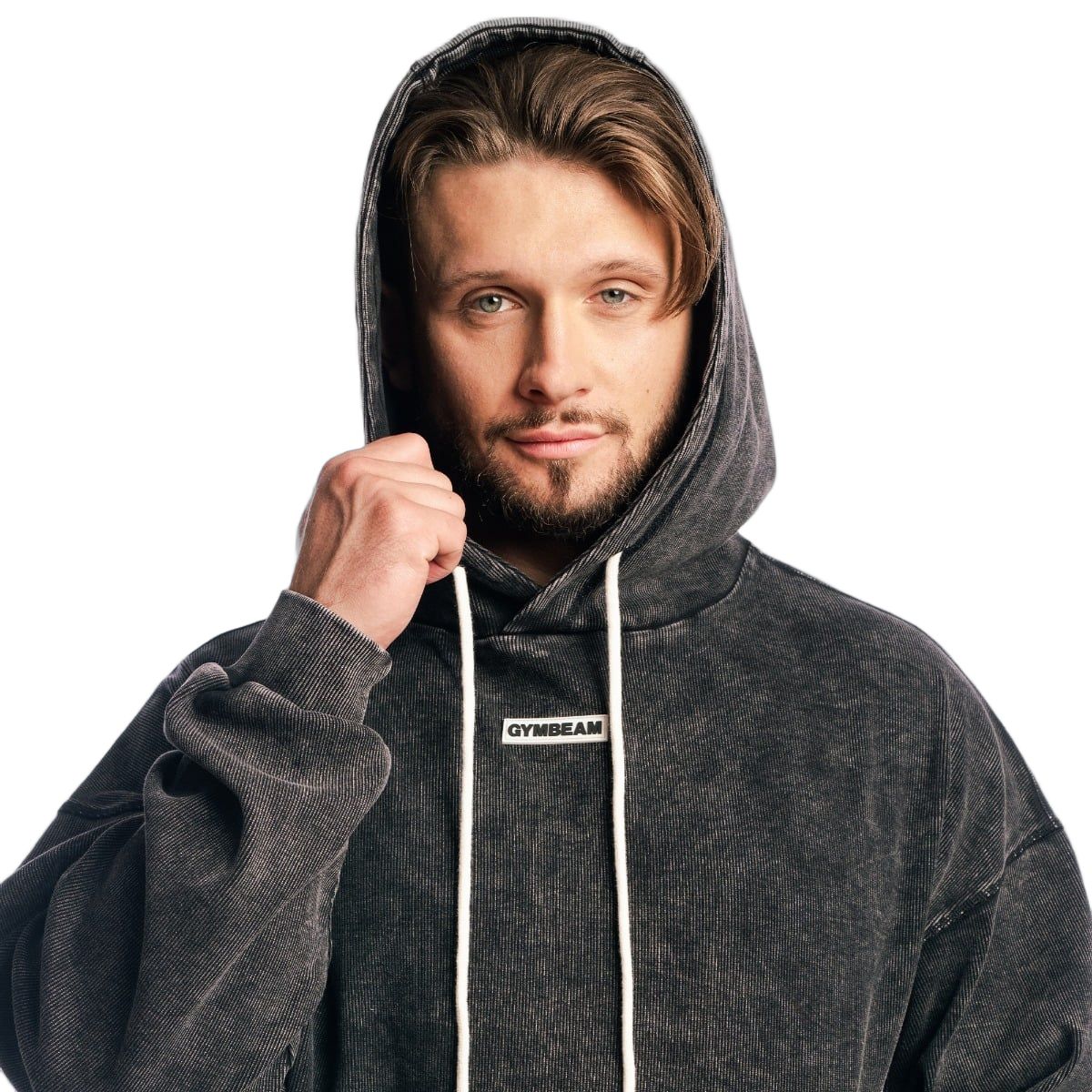 Herren Oversized Hoodie in verwaschenem Schwarz, Kapuze mit Kordelzug. Mann zieht die Kapuze hoch.