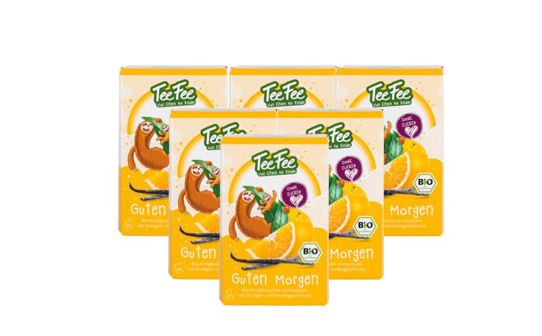 Mehrere Packungen TeeFee Guten Morgen Bio Kräutertee. Gelbe Verpackung mit Logo, Orange und Vanille. Bio-Siegel.