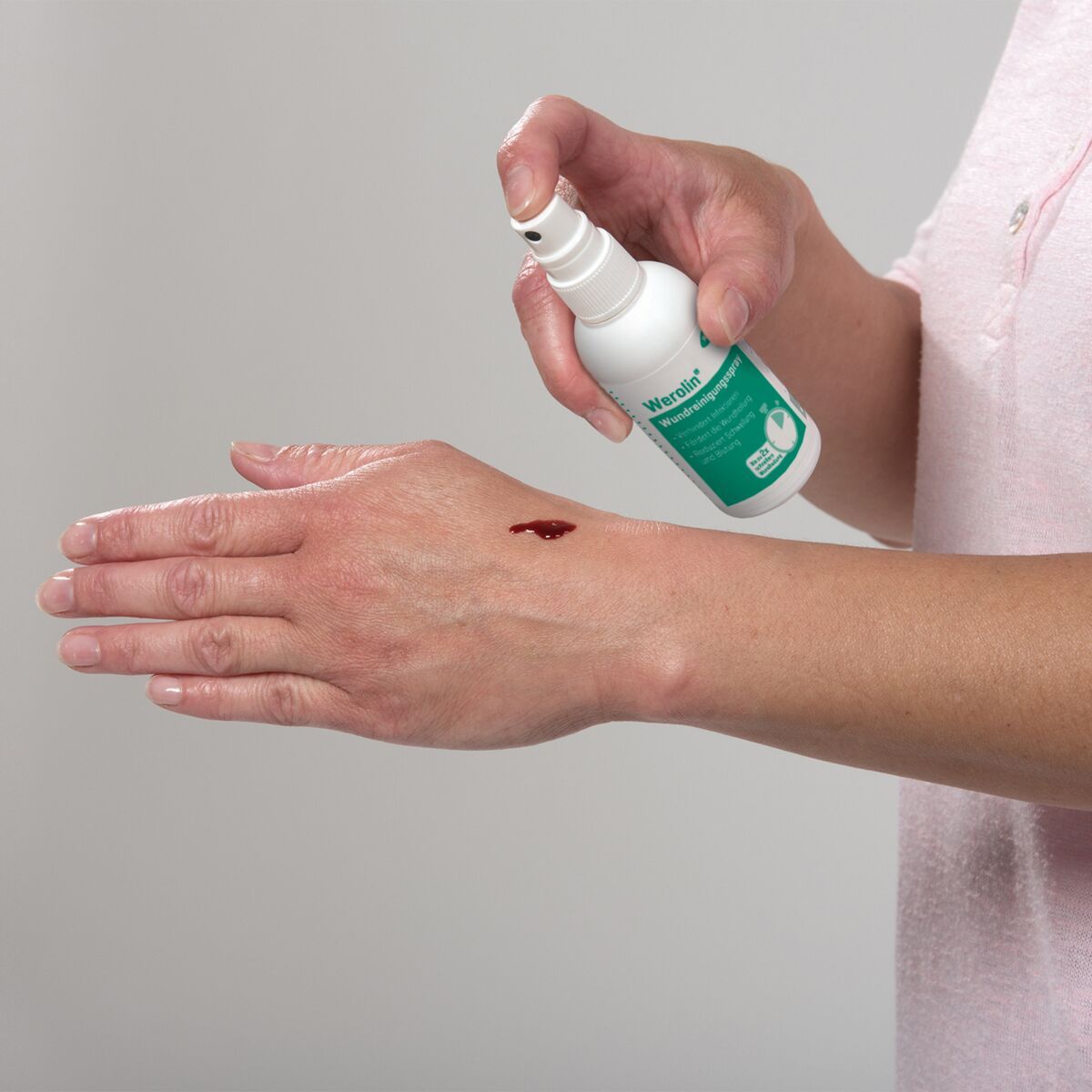 Hand mit kleiner Wunde, auf die ein Spray aufgetragen wird.