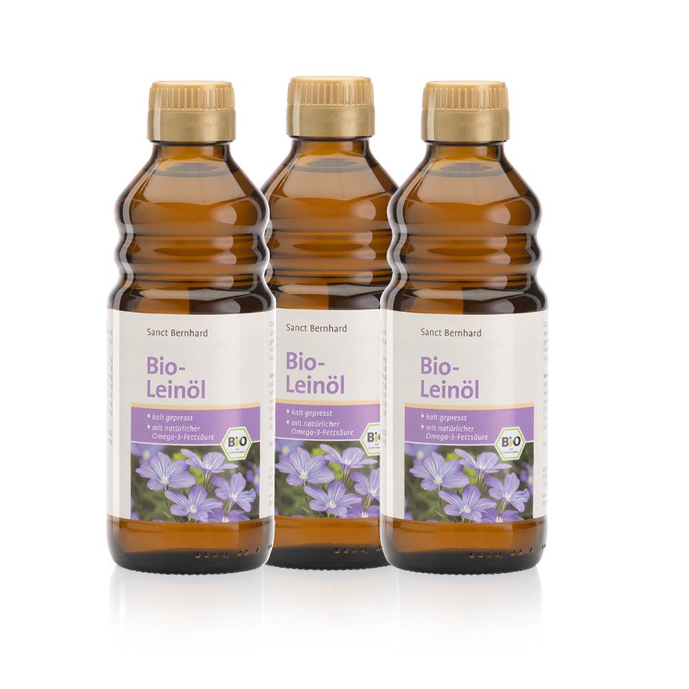 Drei Flaschen Bio-Leinöl mit Etiketten. Braune Glasflaschen mit goldenen Verschlüssen. Etikett mit Produktname, Blumenmotiv und Bio-Siegel.