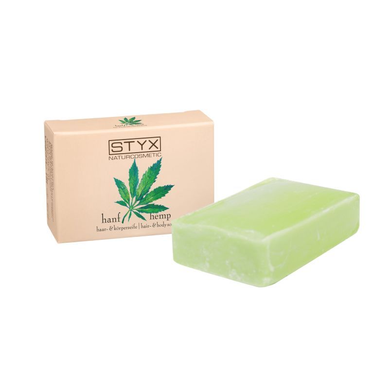 Grüne Seife neben Verpackung. Verpackung mit Logo und Hanfblatt-Illustration. Aufschrift: Hanf, Naturkosmetik.