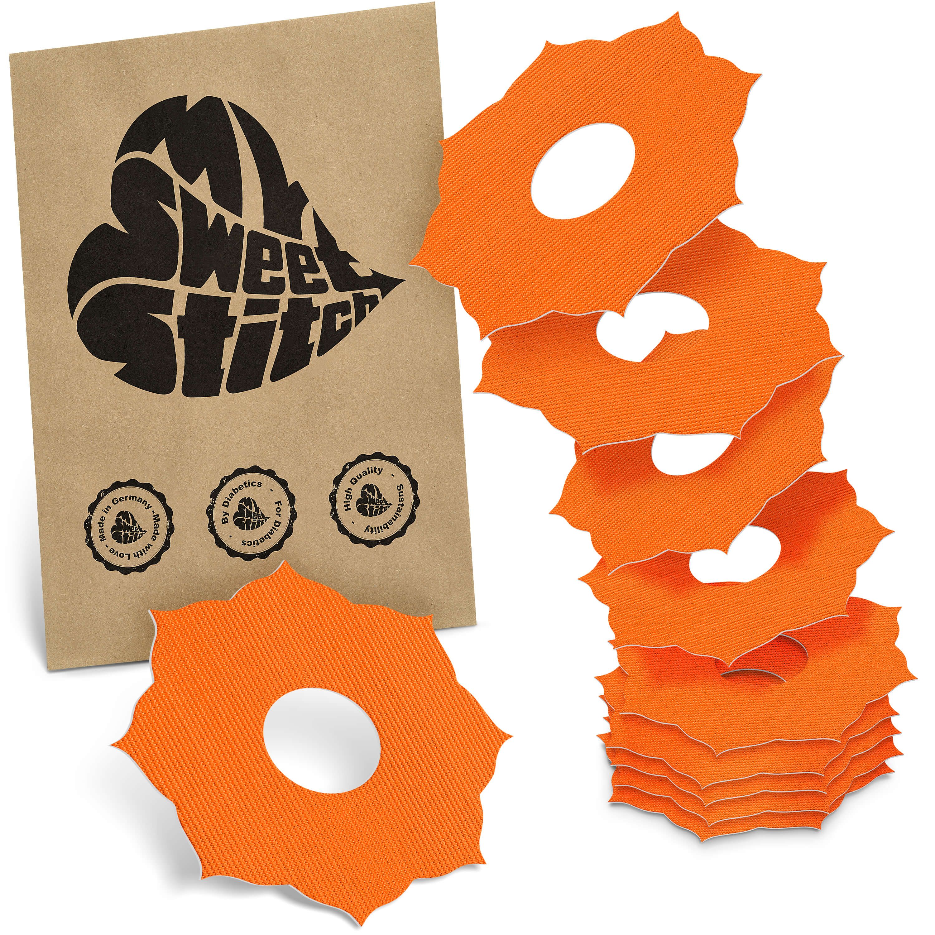 Orange Mandala-förmige Ringpatches mit zentralem Loch, gestapelt neben einer braunen Papiertüte mit Logo.