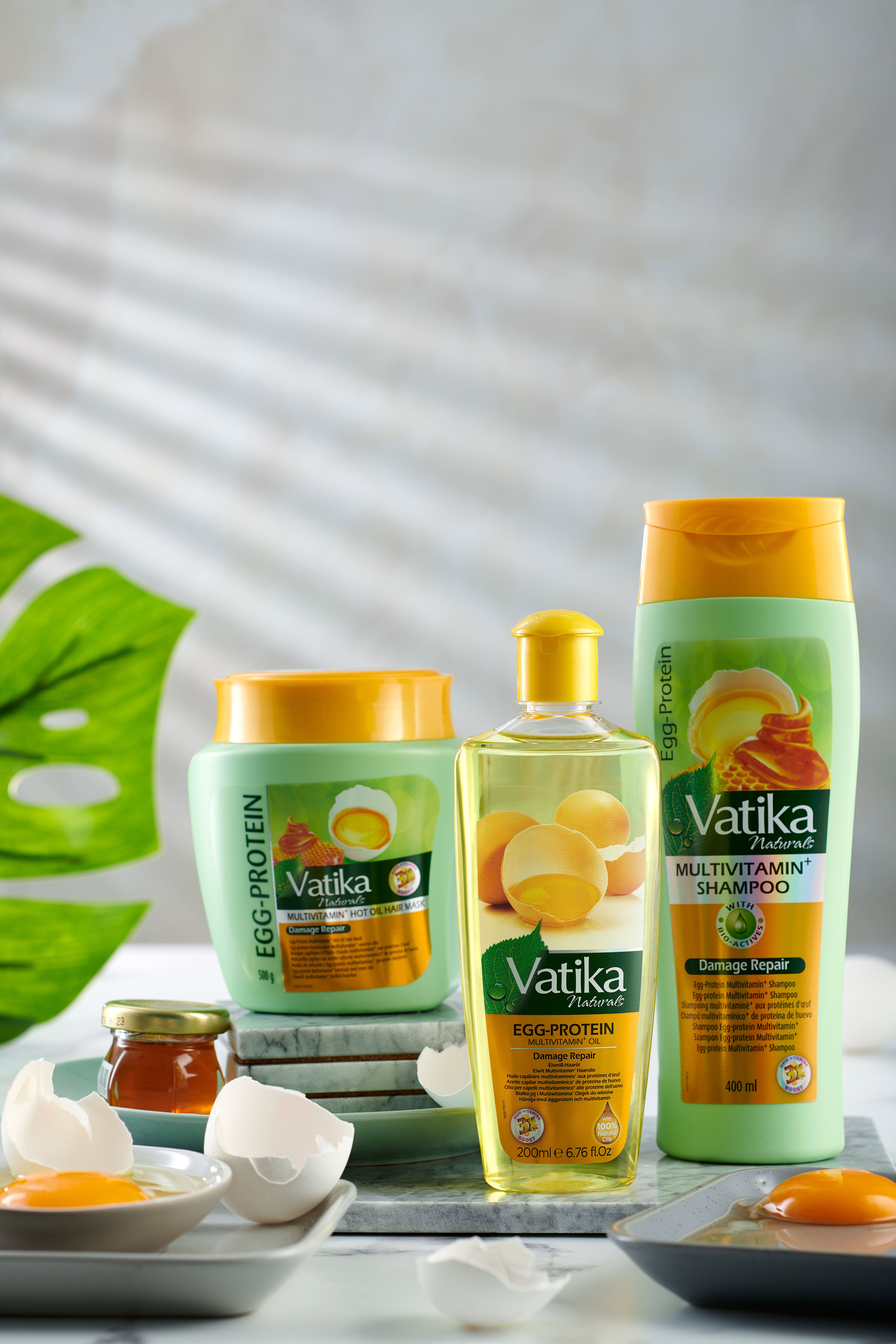 Drei Vatika-Produkte: Shampoo, Haarmaske und Haaröl. Eier und Honig auf einem Tisch.