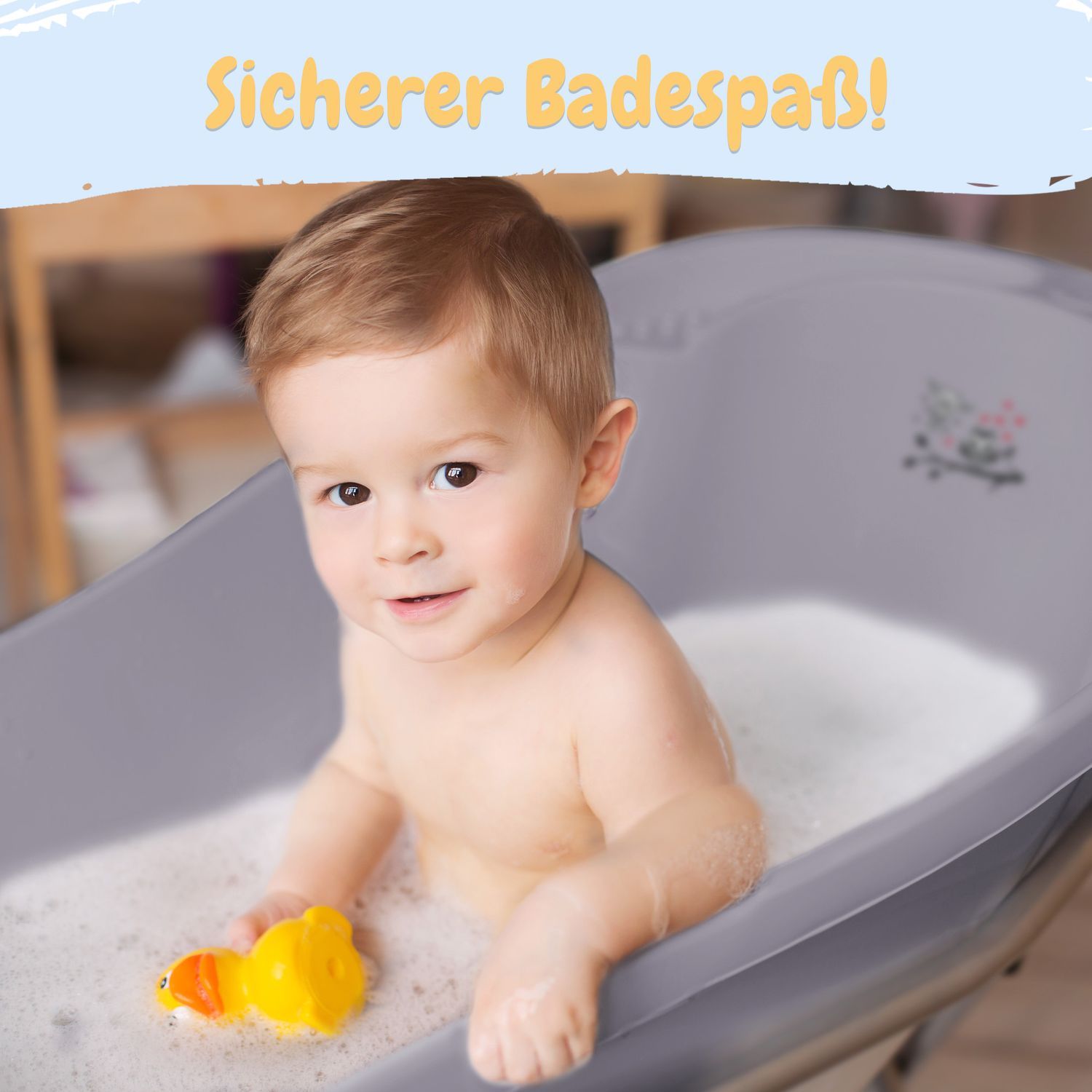 Kleinkind in grauer Babybadewanne mit Wasser und gelber Quietscheente. Sicherer Badespaß!