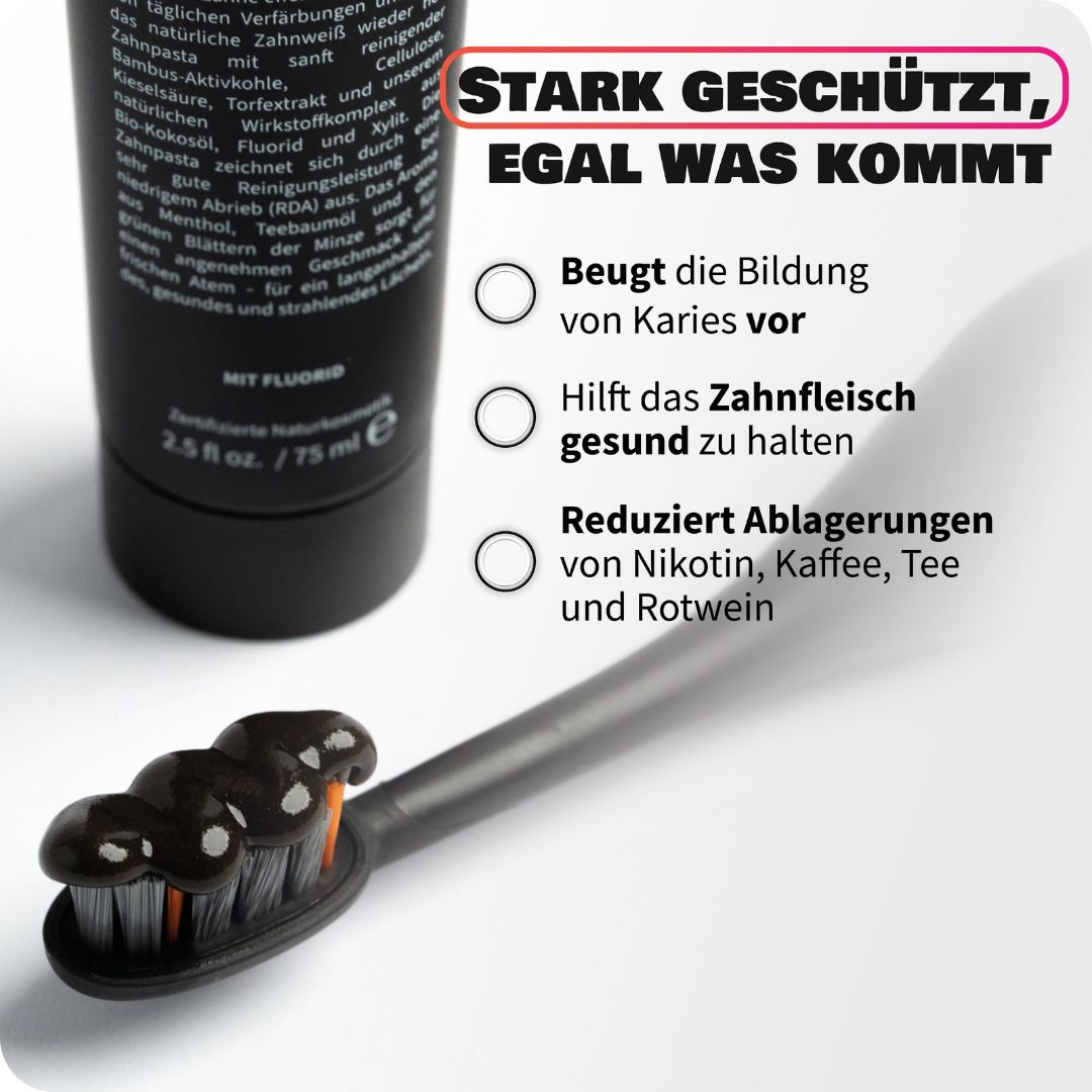Zahnheld Zahnpasta Tube und eine schwarze Zahnbürste mit Zahnpasta, die Schutz vor Ablagerungen zeigt.