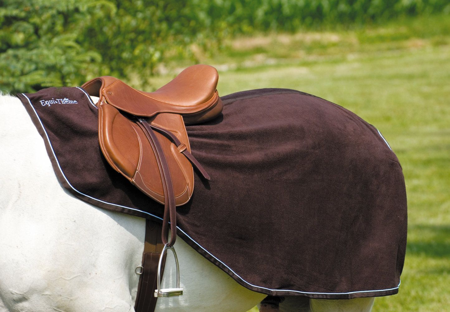 Braune Equi-Theme Nierendecke California mit weißem Rand, unter einem Sattel auf einem Pferd.