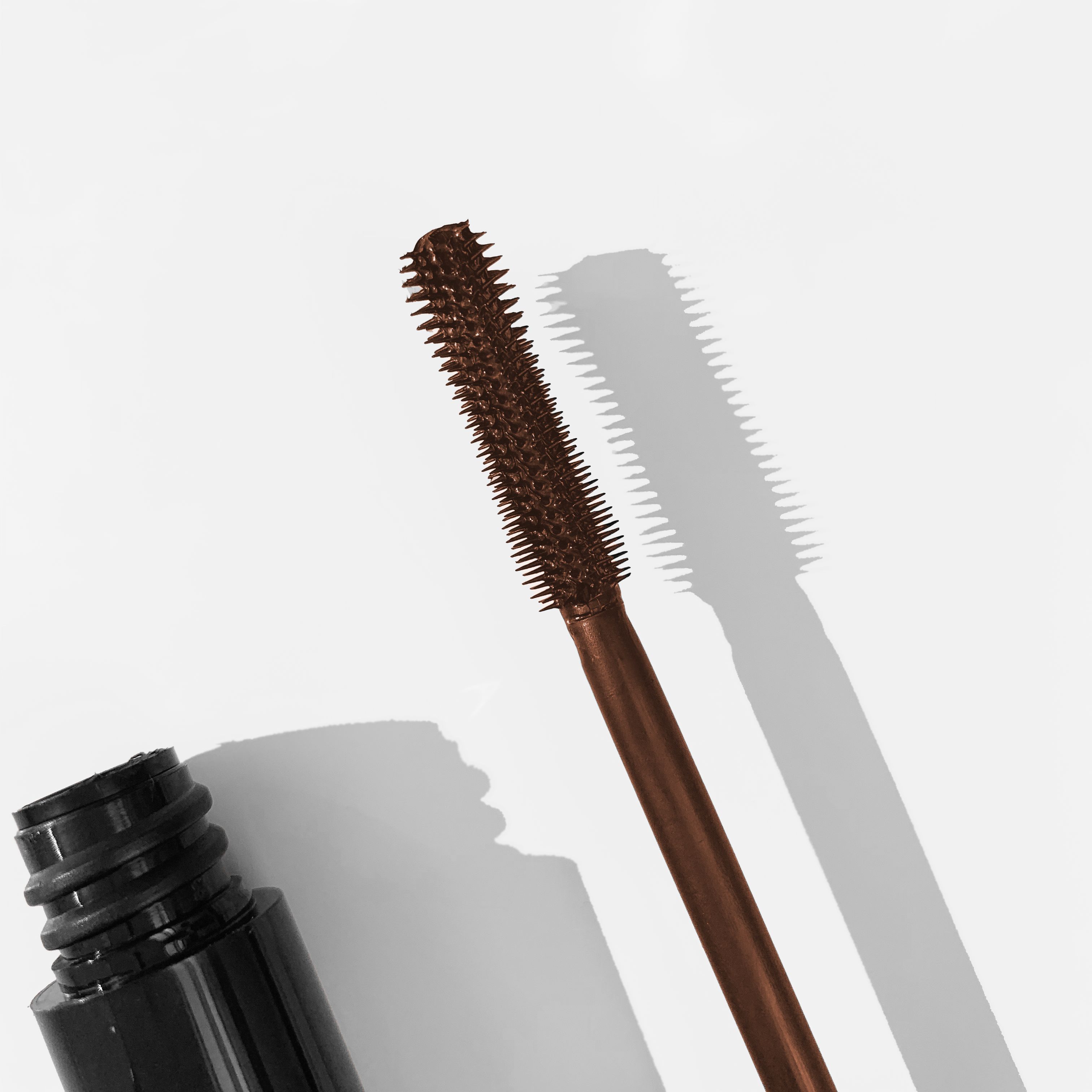Brauner Mascara-Applikator mit Gummiborsten und einem Schattenwurf.