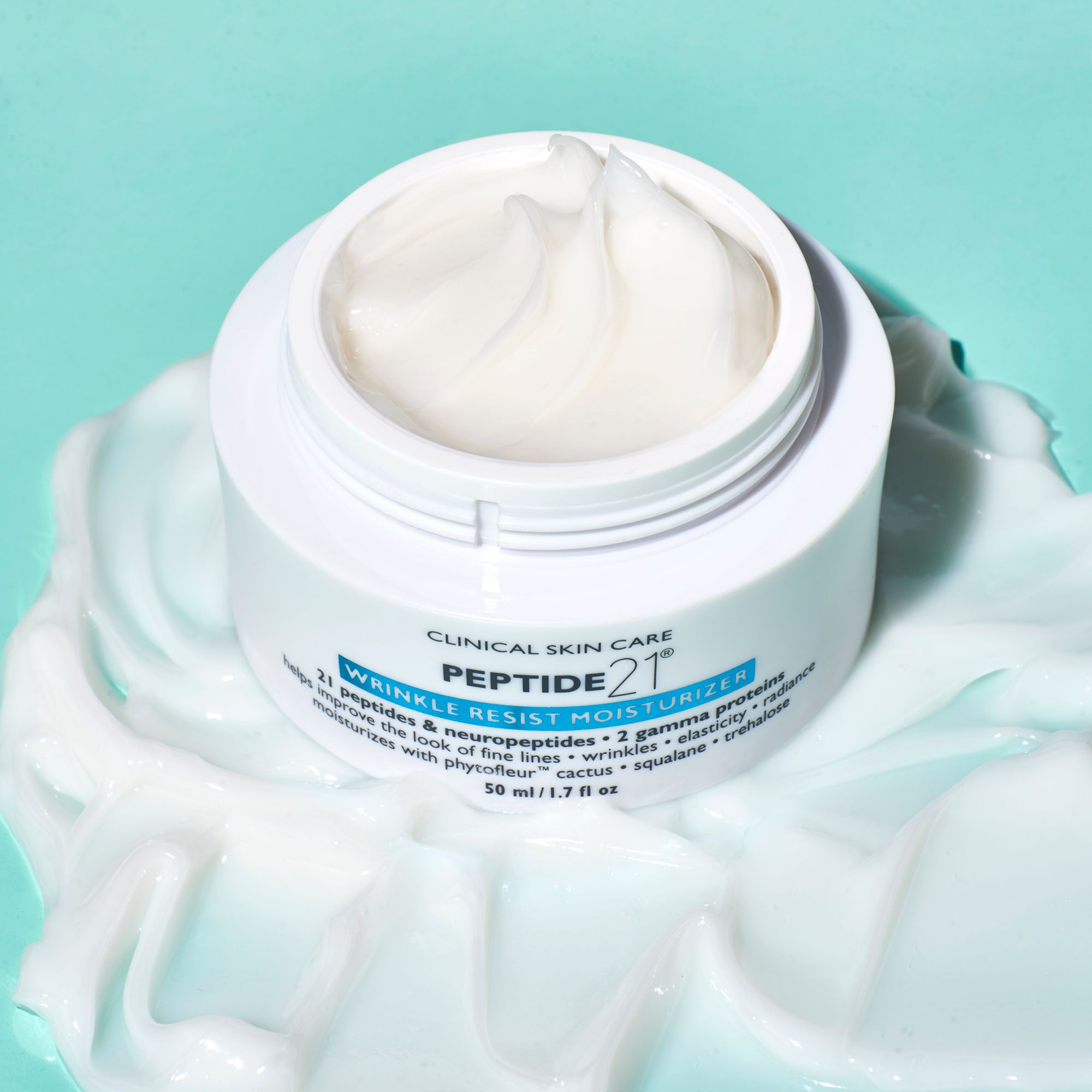 Offener weißer Tiegel mit Creme. Aufschrift: Peter Thomas Roth, Peptide 21 Wrinkle Resist Moisturizer. 50 ml/1.7 fl oz. Creme auf Untergrund.