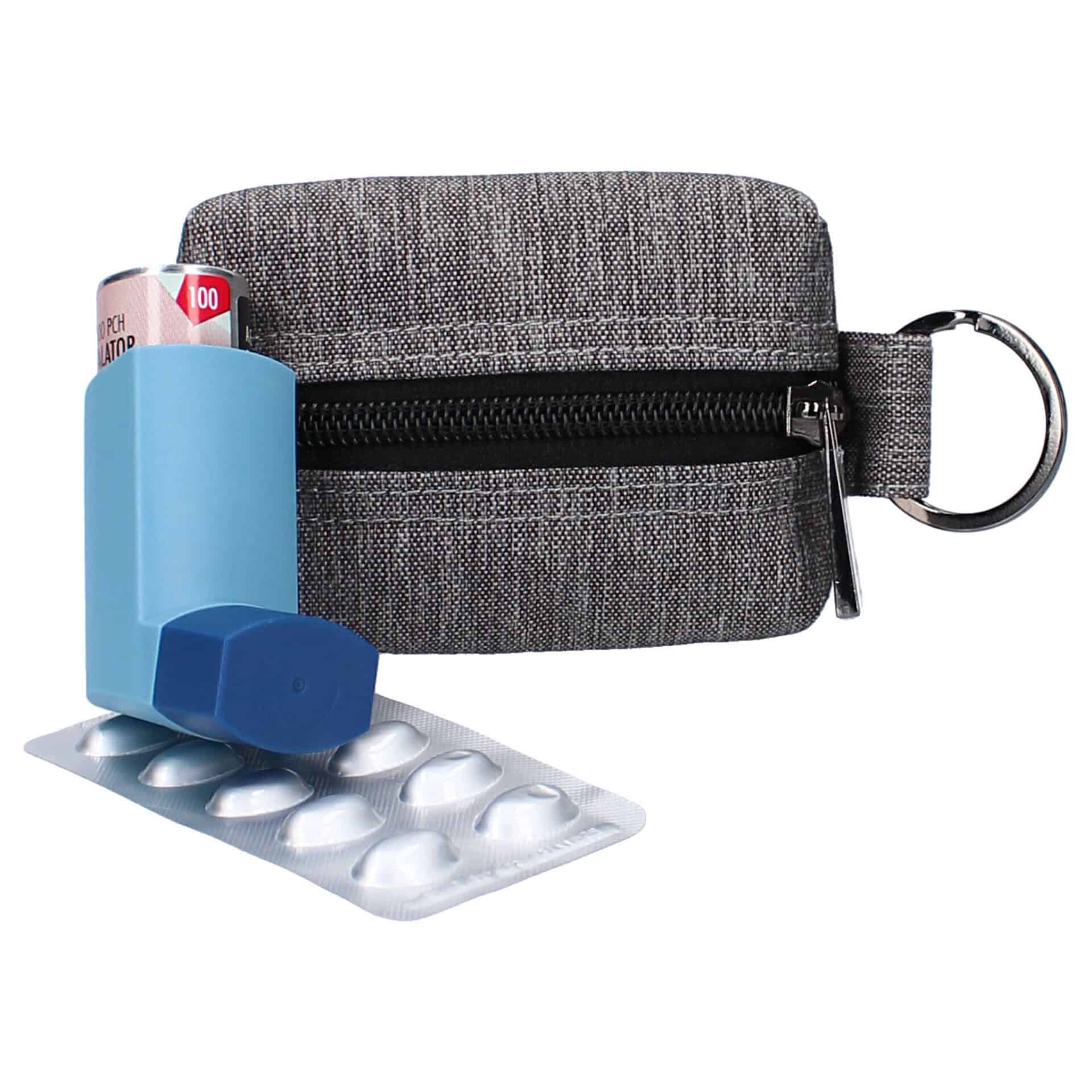 Graue Medikamententasche mit Schlüsselring, geöffnet, zeigt Inhalator und Pillenstreifen.
