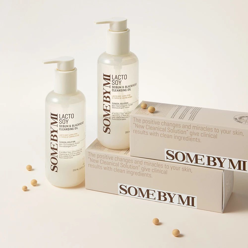 Zwei Flaschen und zwei Schachteln. Aufschrift: SOMEBYMI Lacto Soy Sebum & Blackhead Cleansing Oil. Sojabohnen liegen herum.