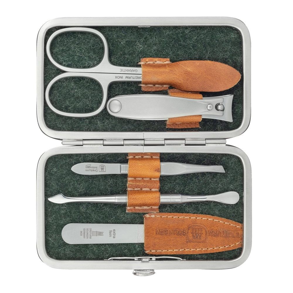 Geöffnetes Etui mit Maniküre-Werkzeugen: Schere, Nagelfeile, Pinzette, Hufstäbchen. Braune Lederdetails.