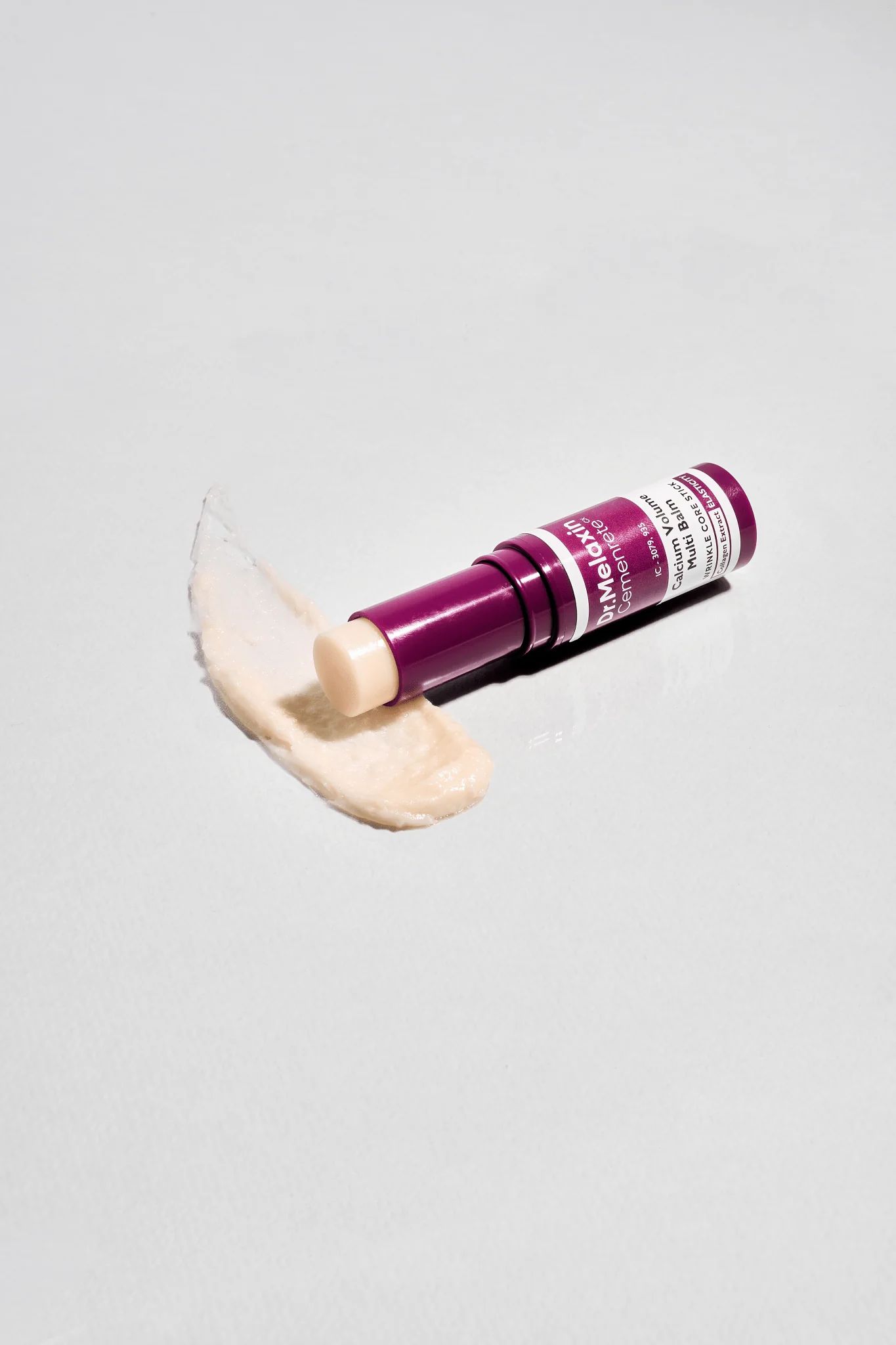 Dr.Melaxin Cemenrete Calcium Volume Multi Balm. Produkt und Produktauftrag auf weißem Hintergrund. Lila Verpackung.