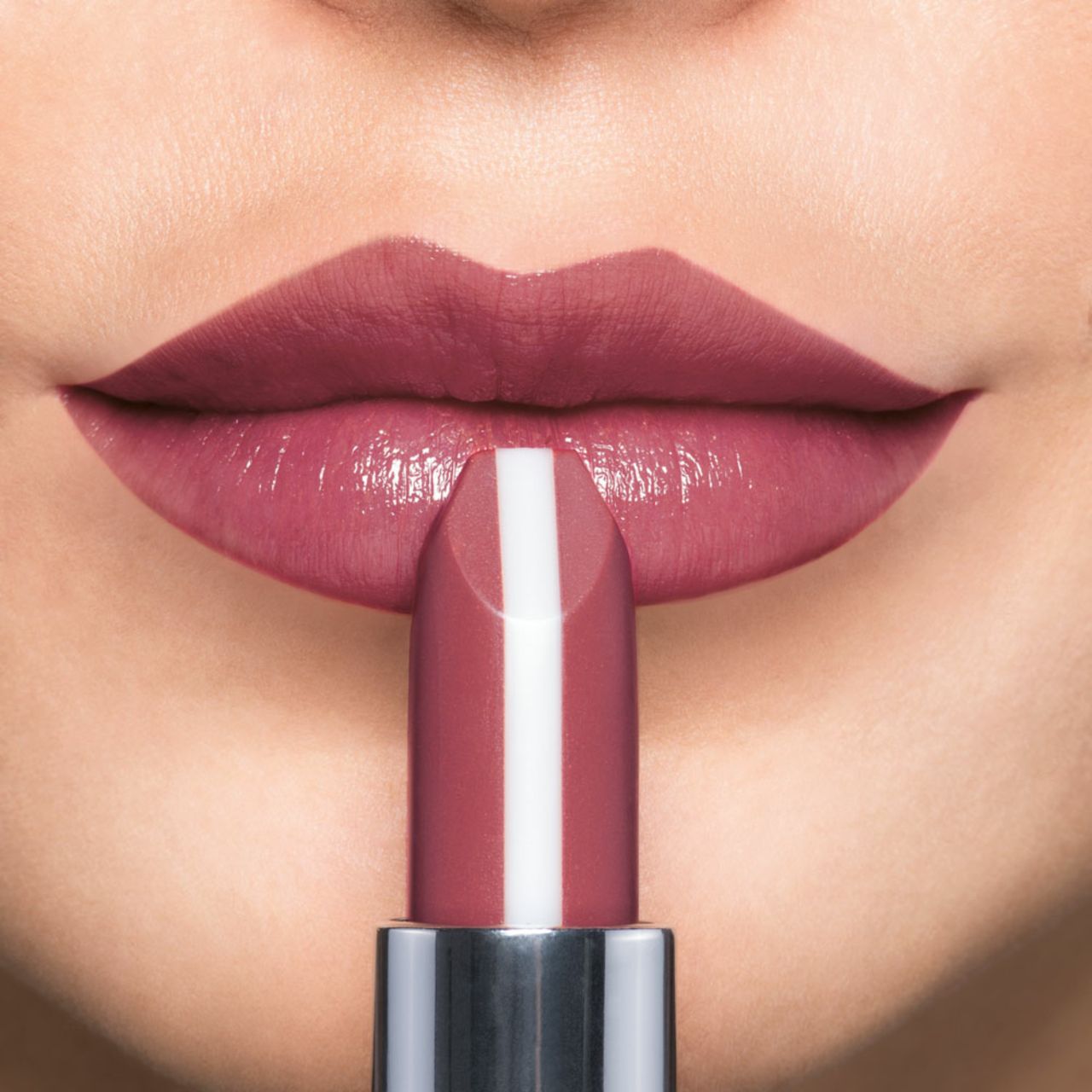 Nahaufnahme von Lippen, die mit einem rosafarbenen Lippenstift bemalt werden. Der Lippenstift hat einen weißen Streifen.