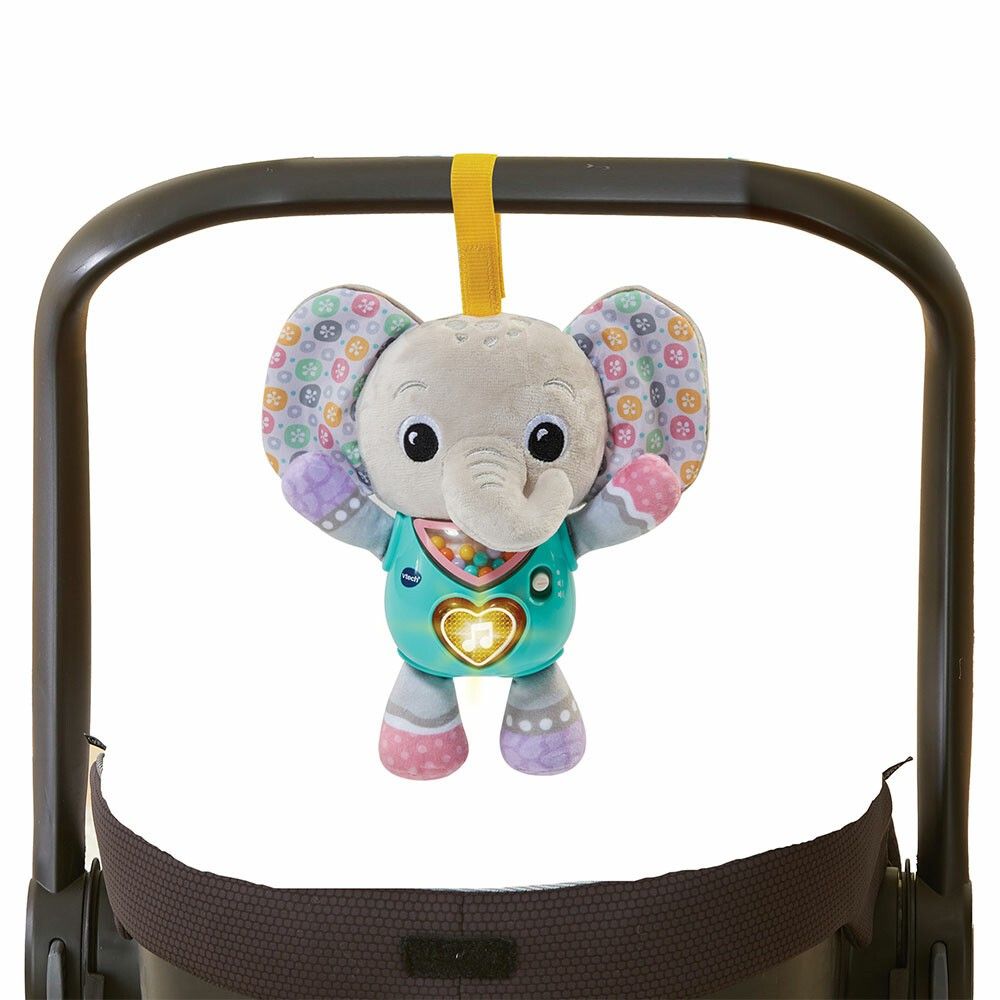 Grauer Elefant mit bunten Ohren, an einem Kinderwagen befestigt. Türkisfarbener Bauch mit Herz und VTech-Logo. Gelbe Schlaufe.