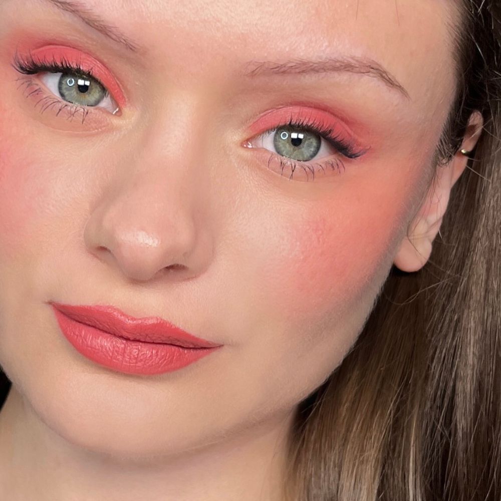 Nahaufnahme eines Gesichts mit Make-up. Rosa Lidschatten, Rouge und Lippenstift. Grüne Augen.