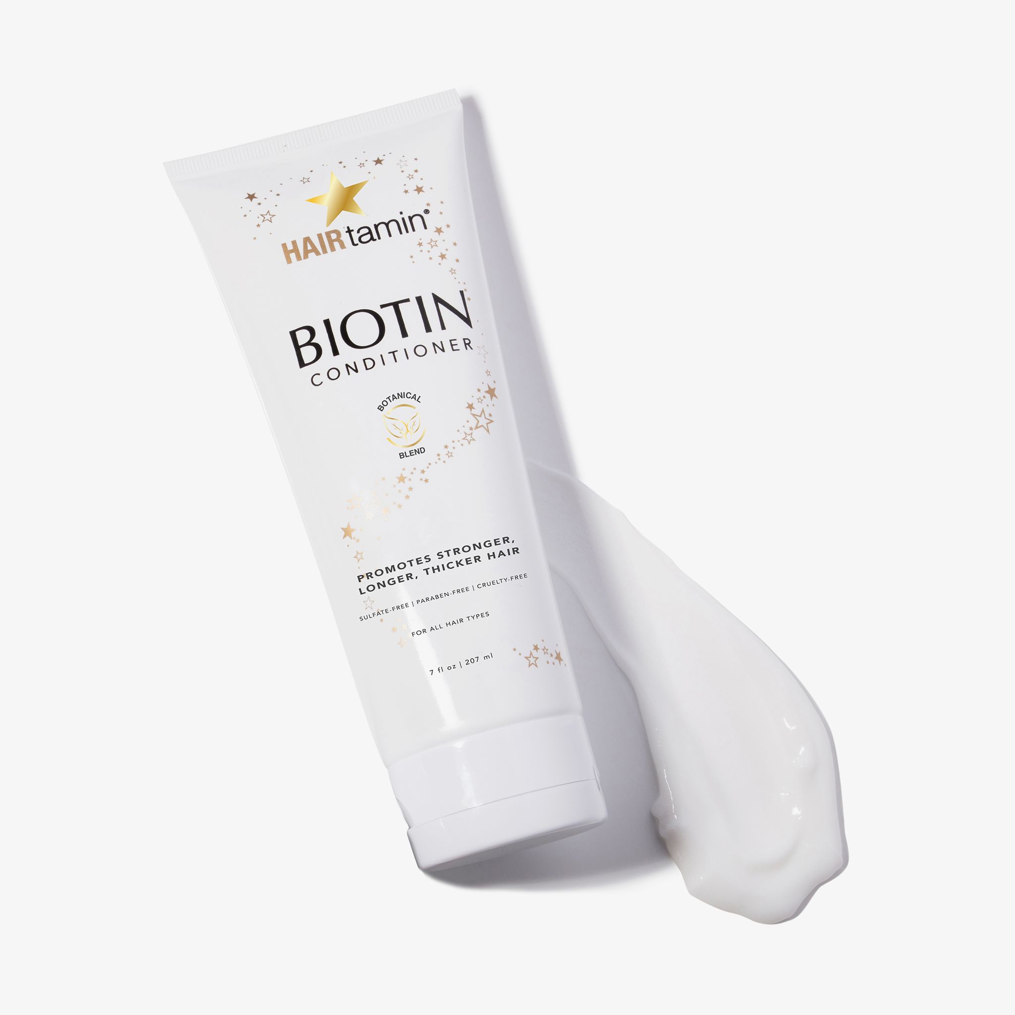 Weiße Tube "HAIRtamin Biotin Conditioner". Produkt wird aus der Tube gedrückt. "Botanical Blend". Für alle Haartypen.