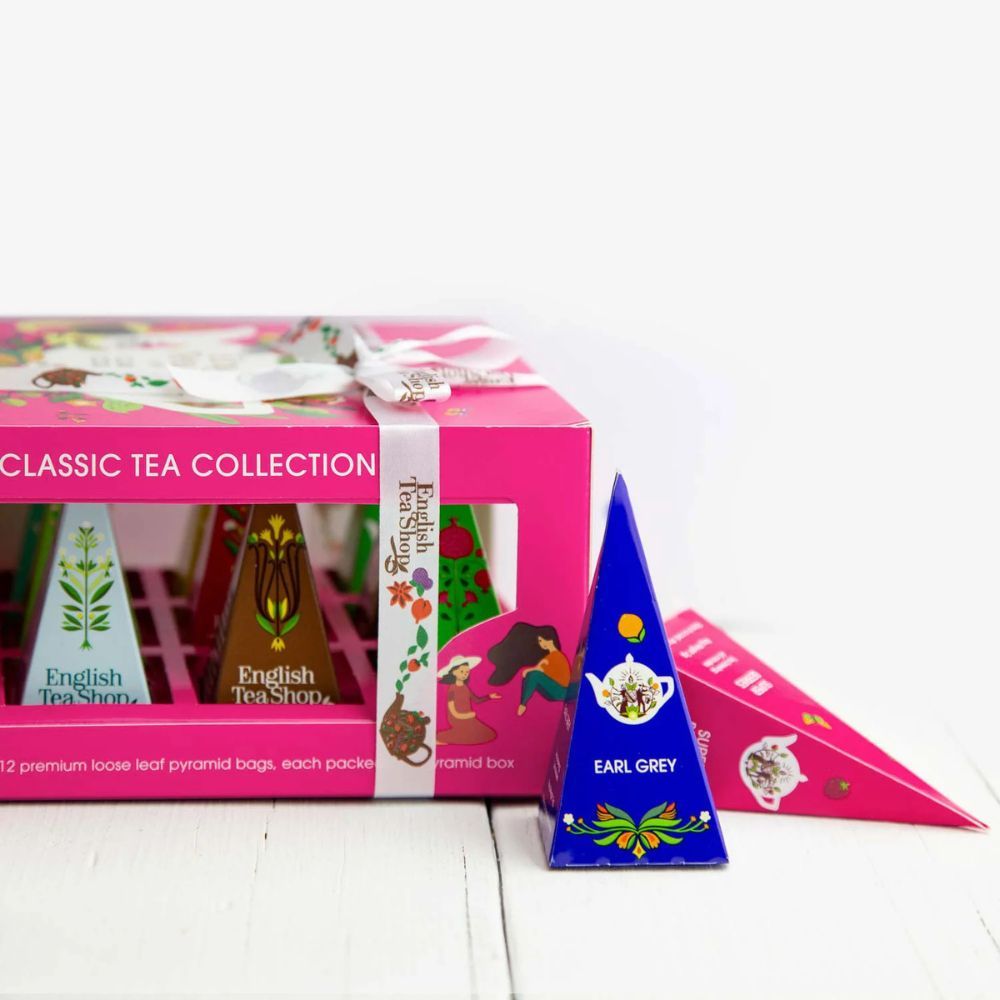 Rosa Geschenkbox mit Teebeuteln. Blaue und rosa Pyramidenboxen liegen daneben. Aufschrift: English Tea Shop Classic Tea Collection.