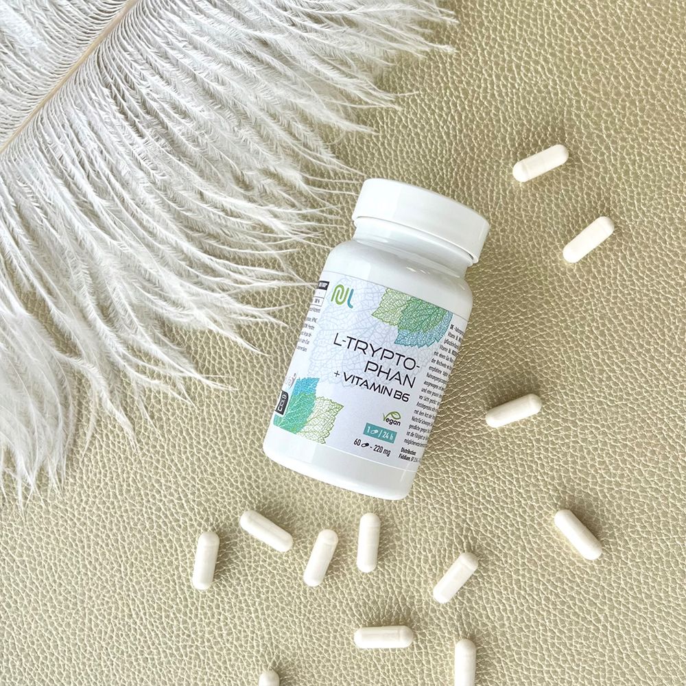 Weiße Kapseln und Flasche. Aufschrift: L-Tryptophan + Vitamin B6. Vegan-Siegel. Flasche auf beigem Untergrund.