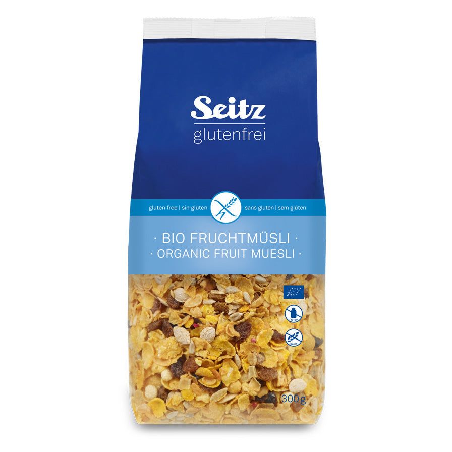 Verpackung mit Bio-Früchtemüsli. Blaue Oberseite mit Logo und Schriftzug 'Seitz glutenfrei'. Sichtbares Müsli mit Früchten.