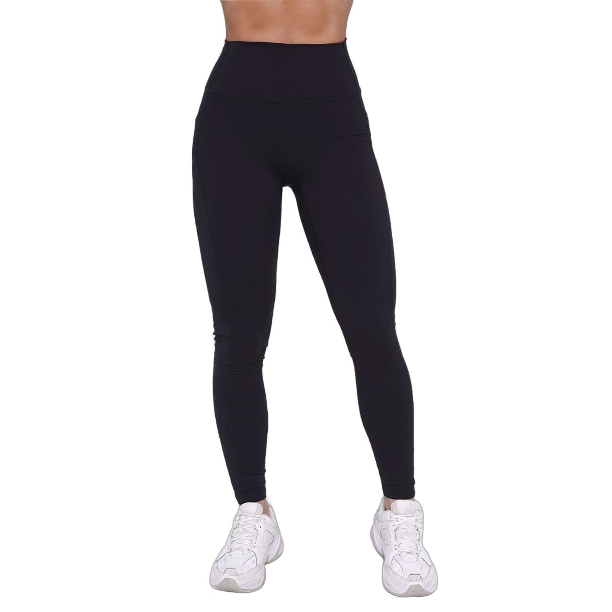 Frau in schwarzen Leggings mit hoher Taille und weißen Turnschuhen.